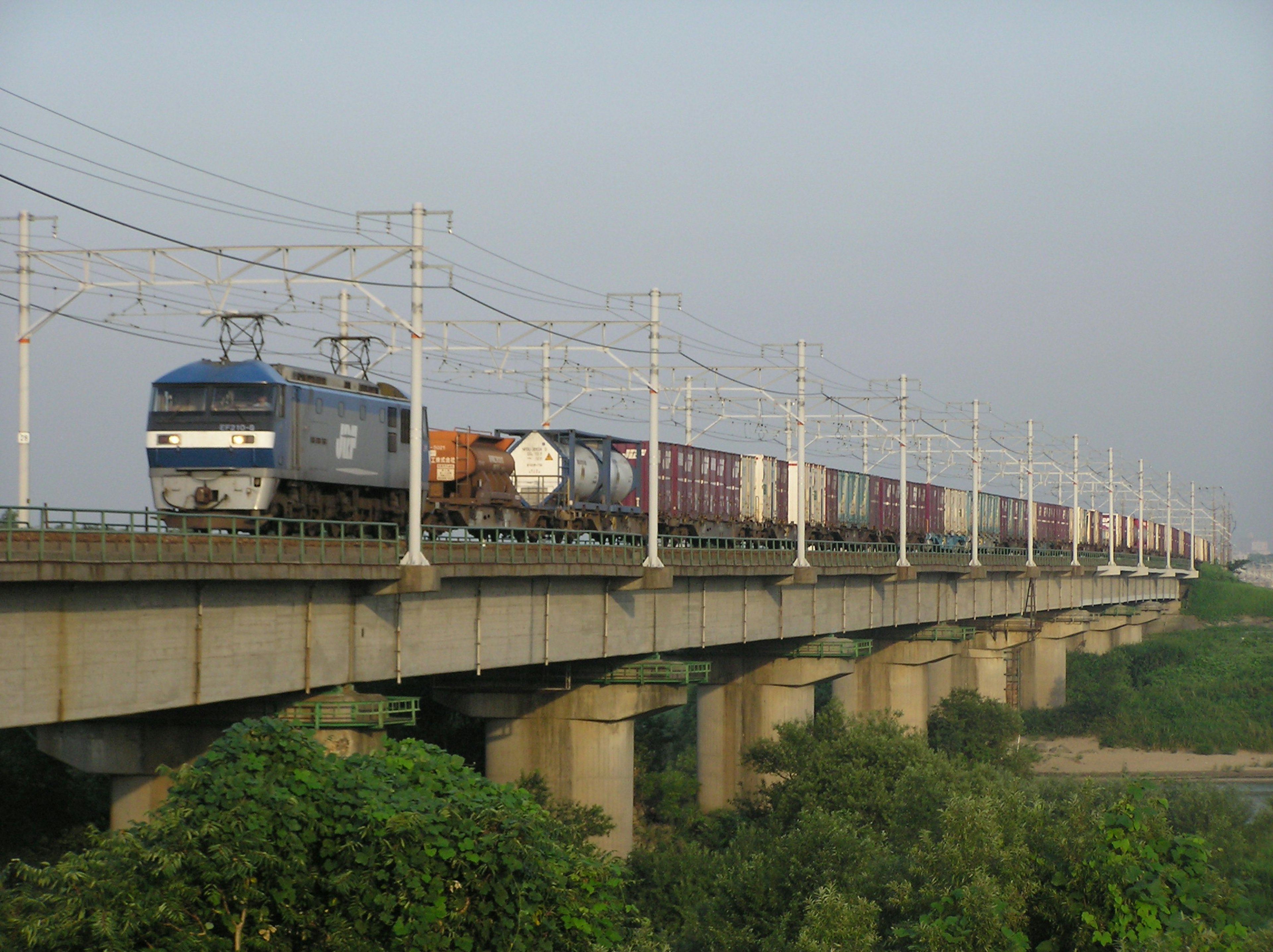 Train de marchandises circulant sur un pont avec un paysage vert