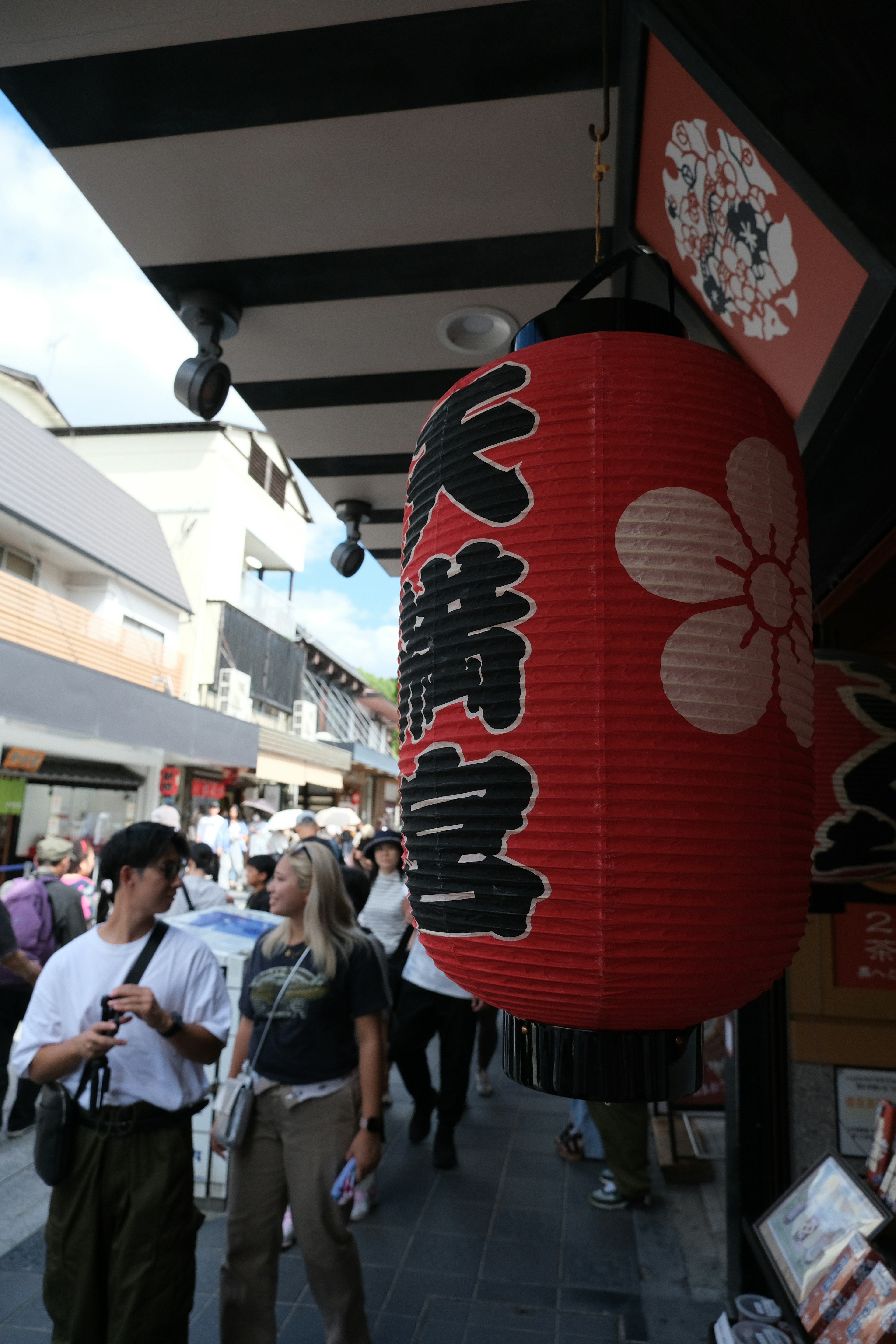 Street scene featuring a red lantern with flower design and bustling crowd