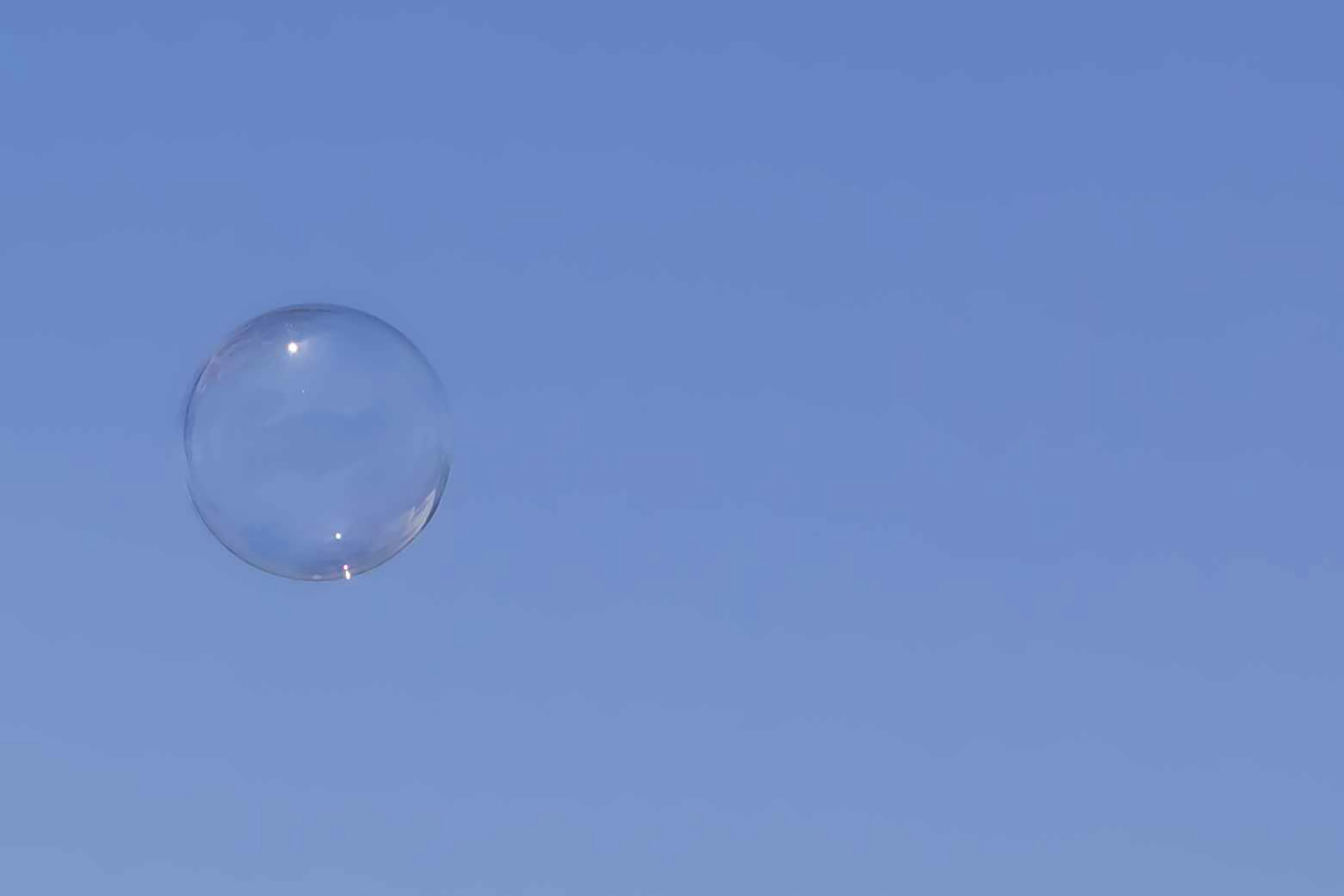 Una burbuja de jabón transparente flotando en un cielo azul