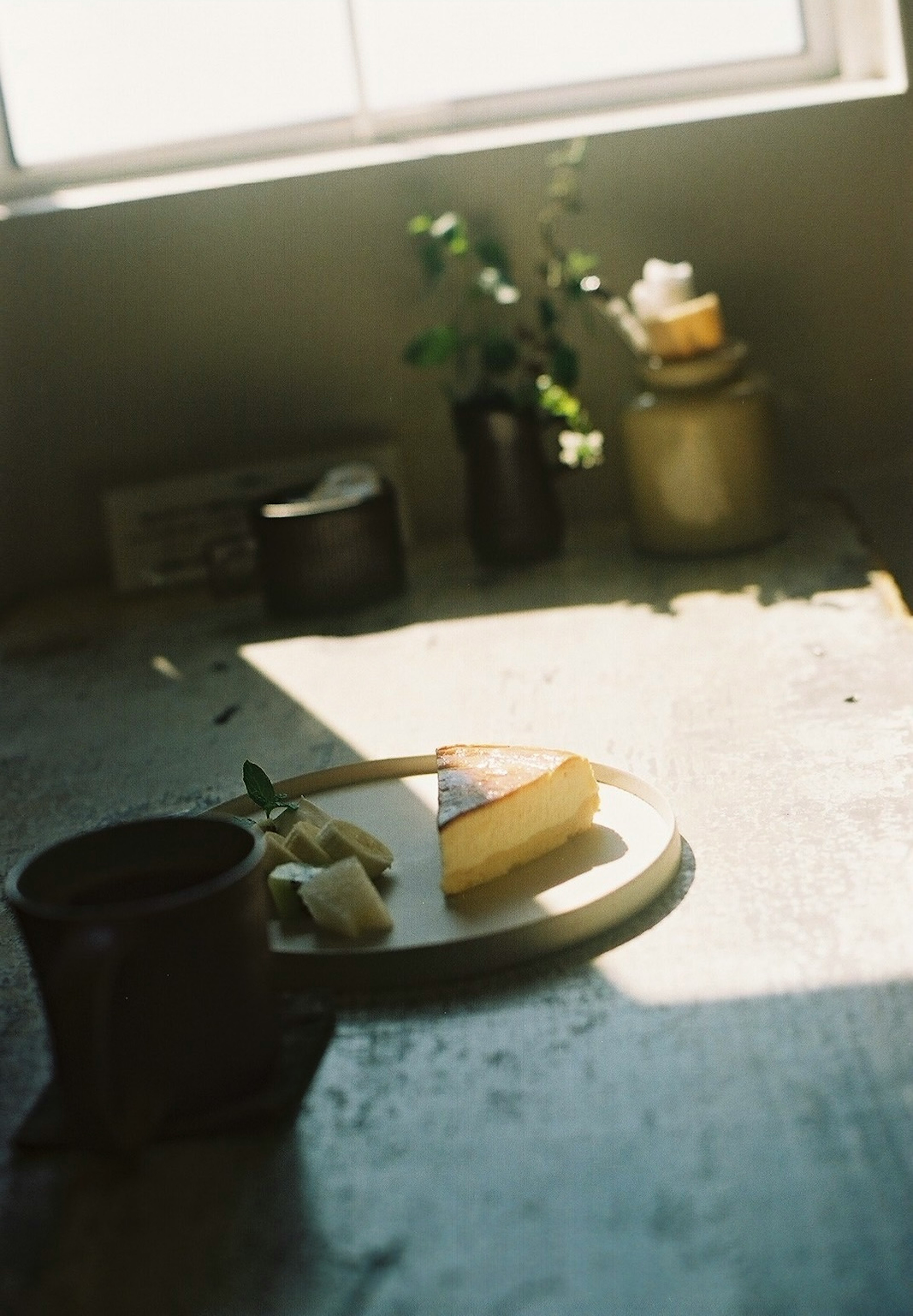 Una foto de un arreglo de queso y frutas en una mesa con luz natural que entra por una ventana