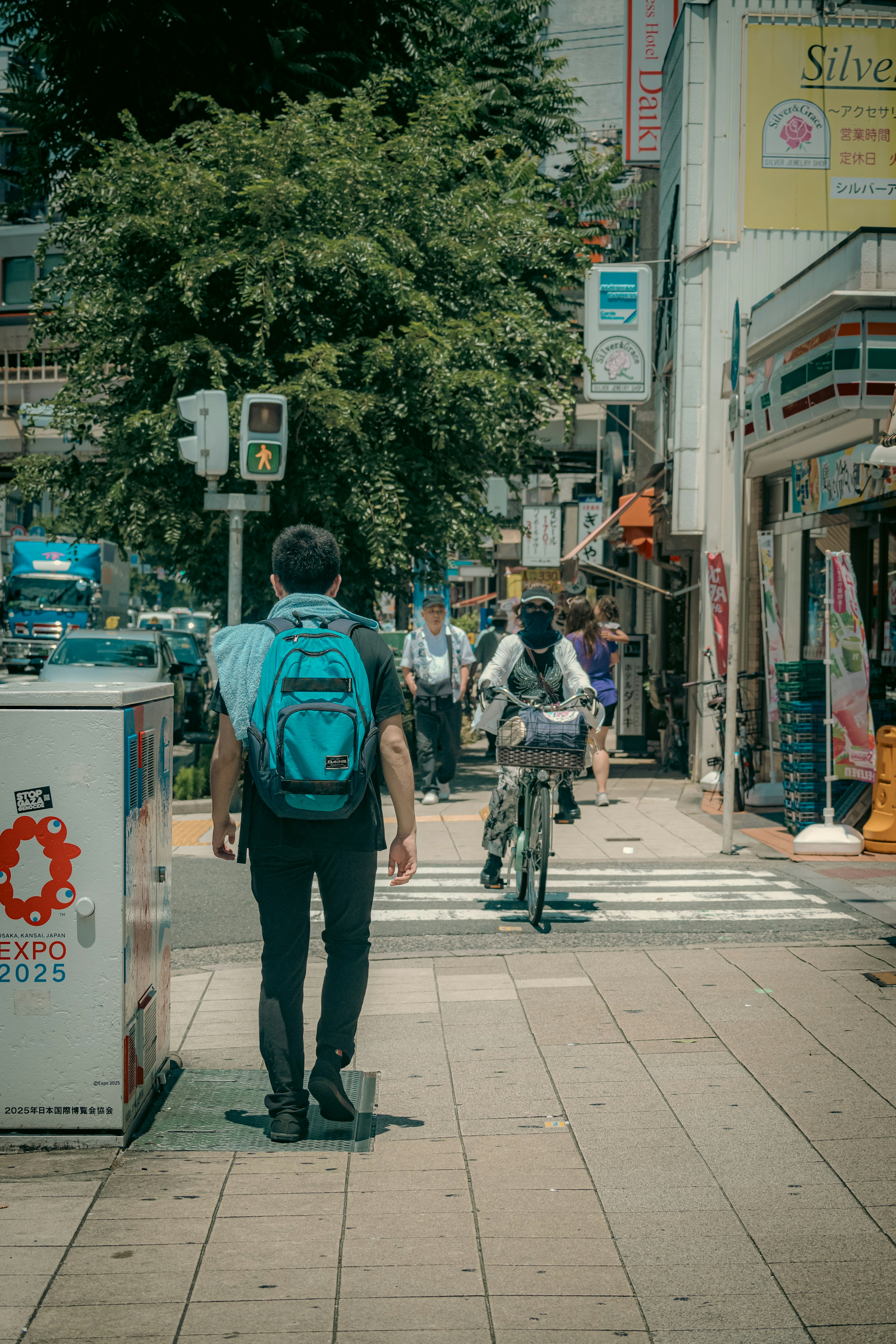 Un hombre con una mochila azul caminando por un paso de peatones en un entorno urbano