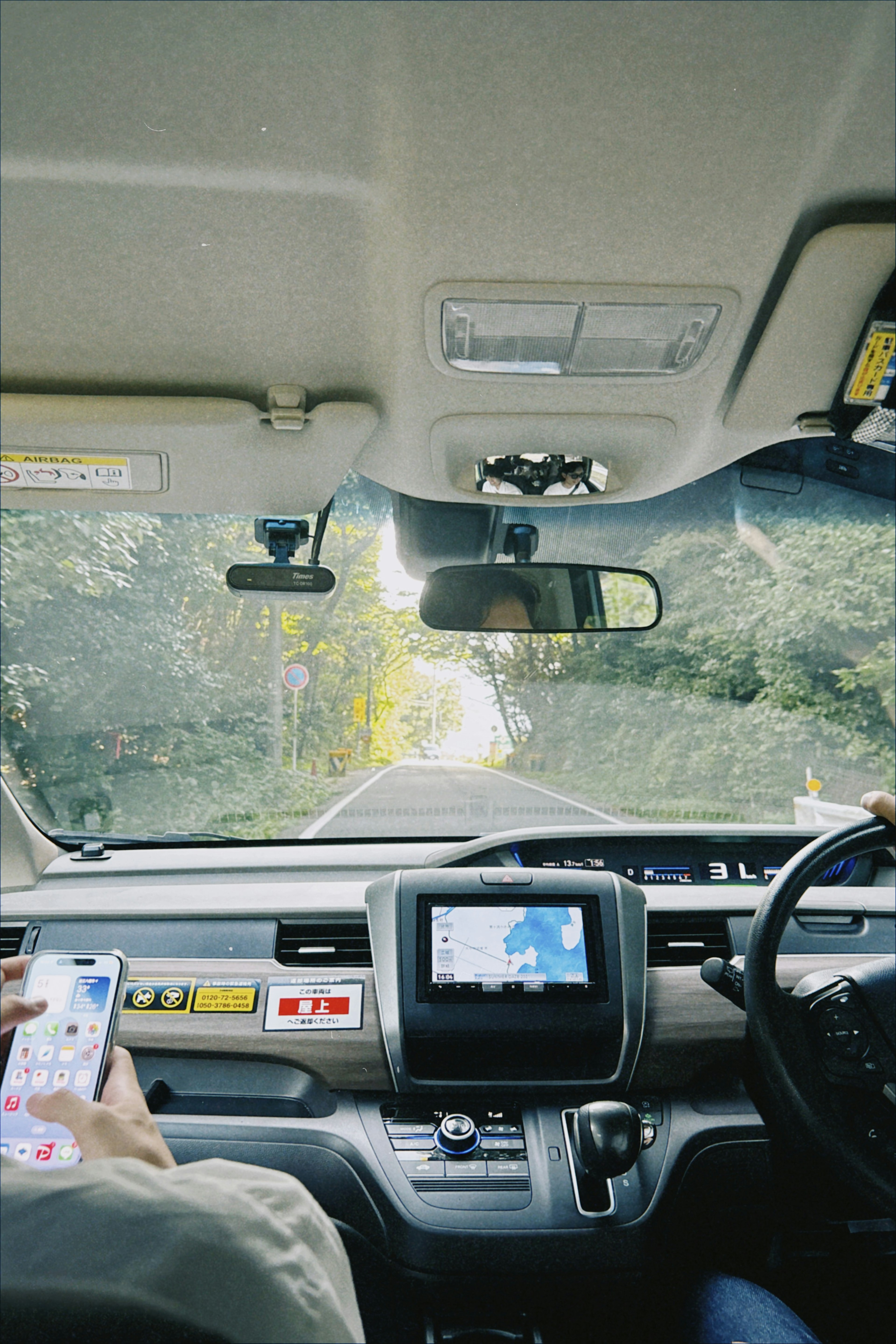 Vista interna di un'auto che mostra il cruscotto e la strada con il display di navigazione