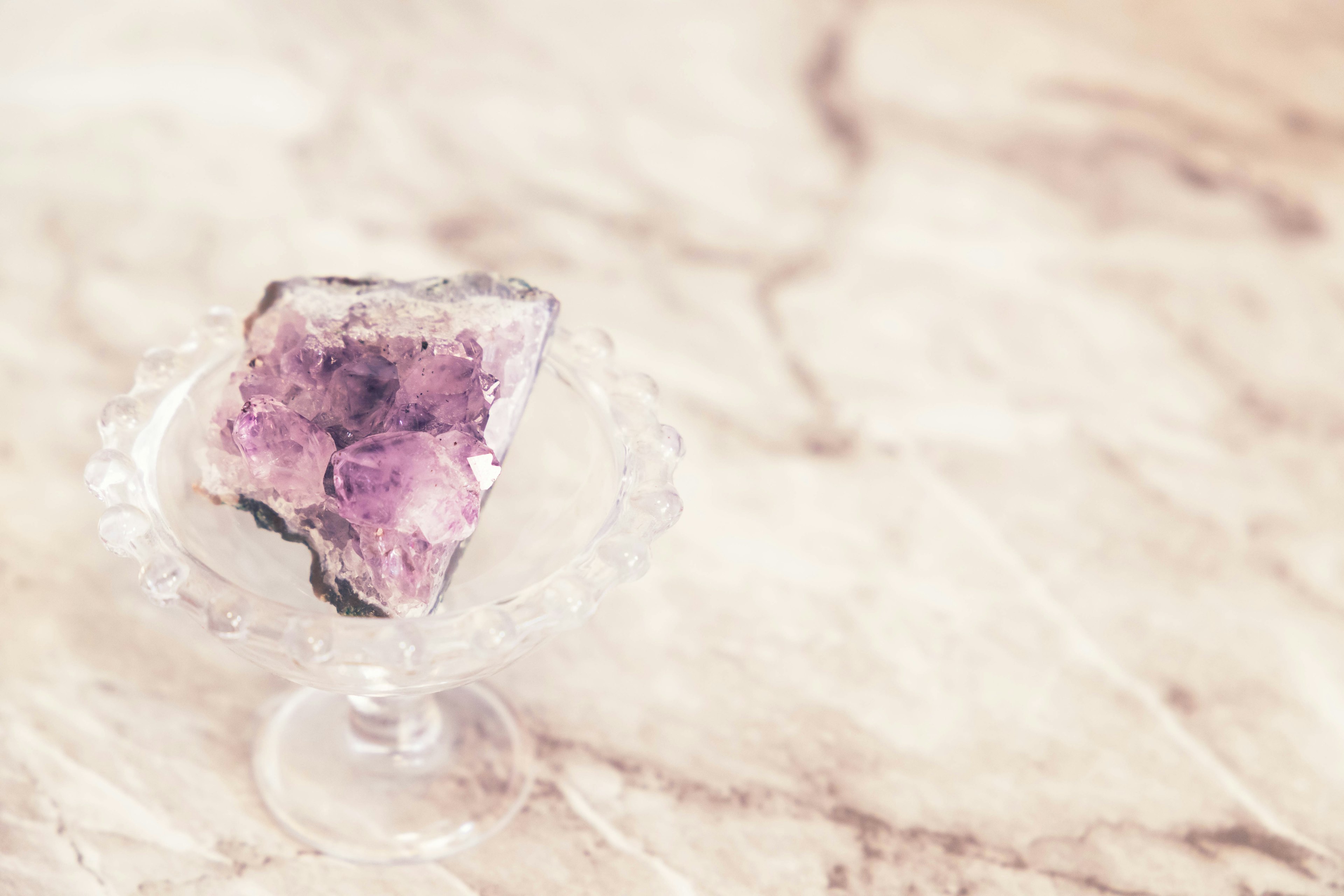 Purple amethyst crystal placed in a clear glass dish