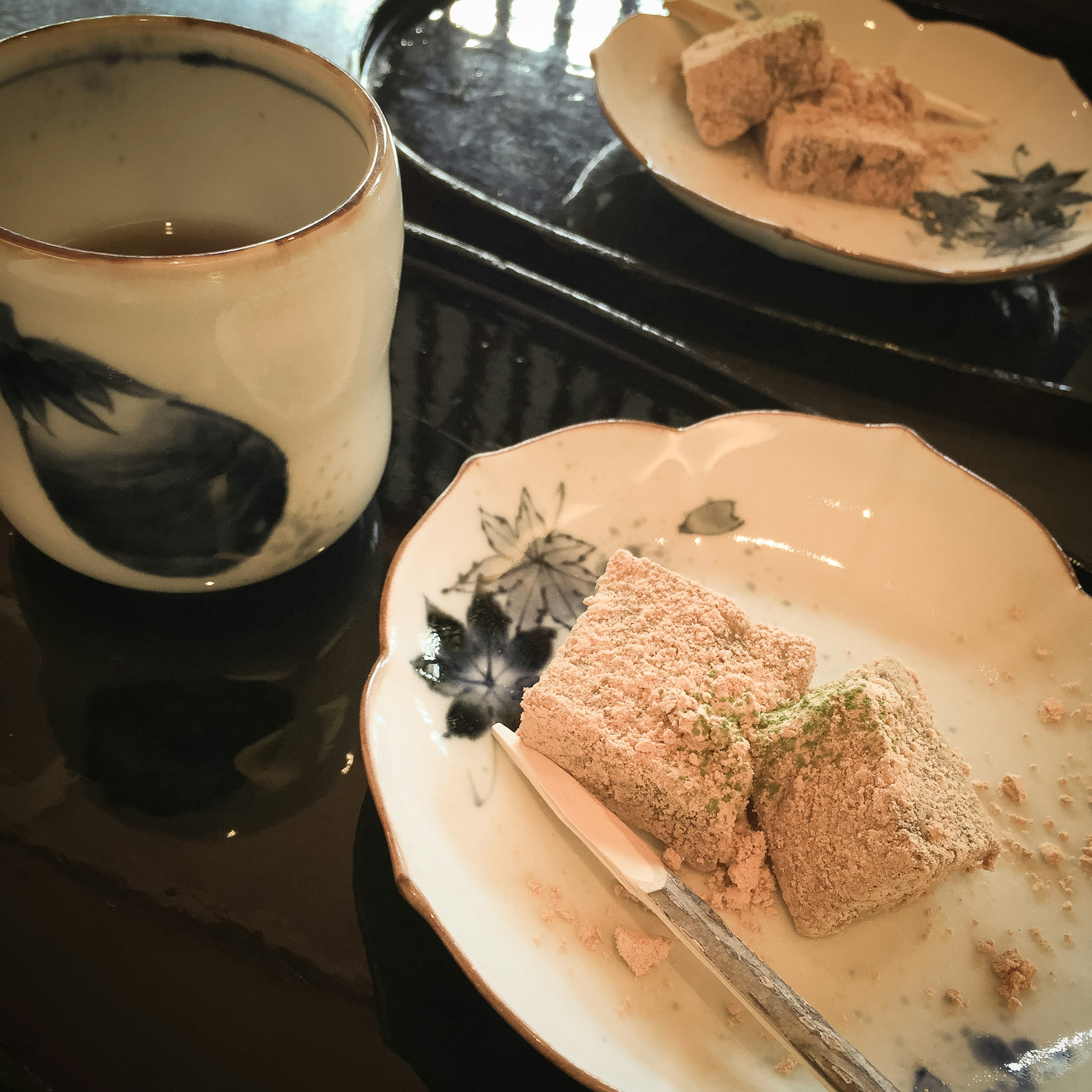 Una taza de té y un trozo de confitería japonesa en un plato