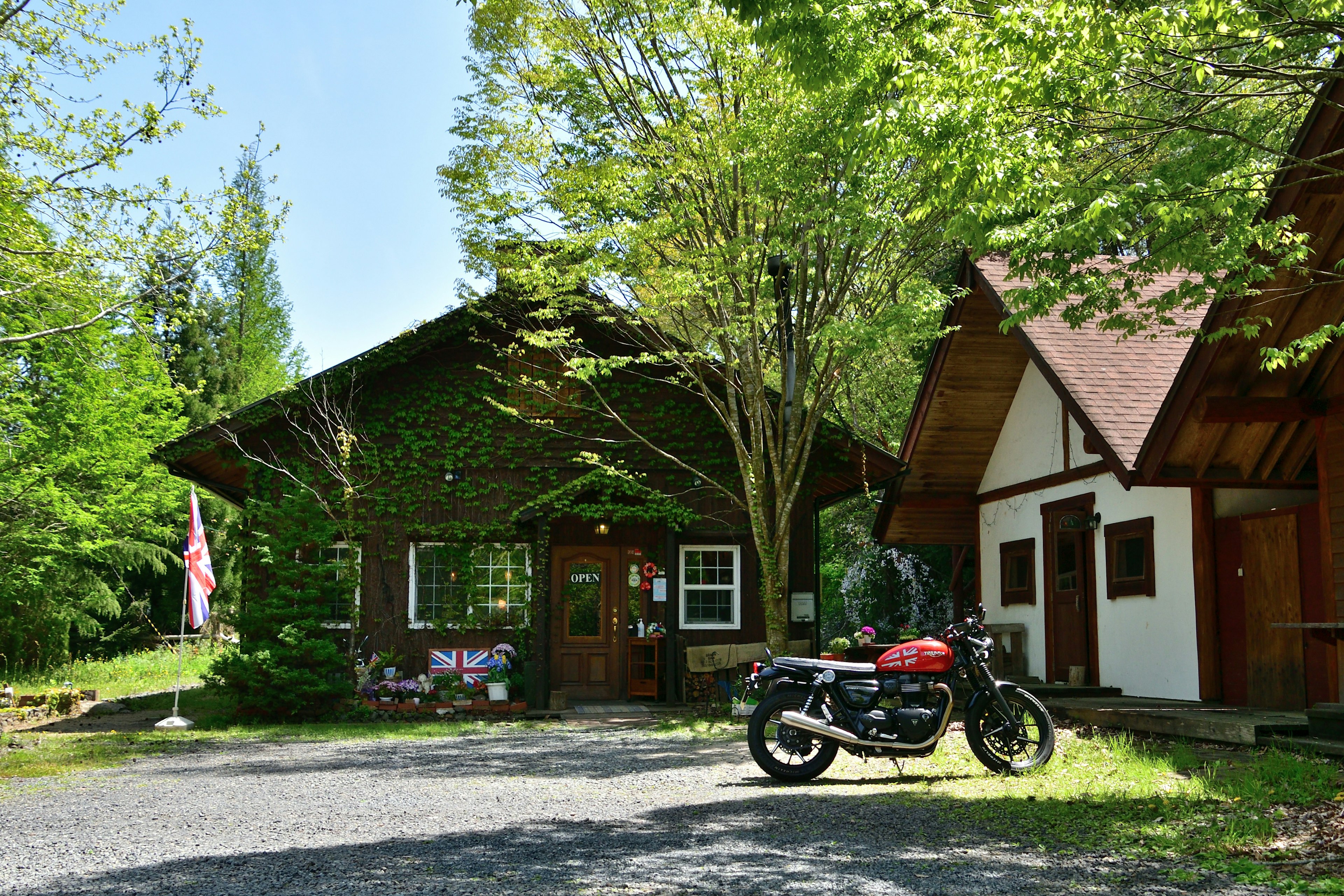 Scenic view of a cottage surrounded by greenery with a motorcycle