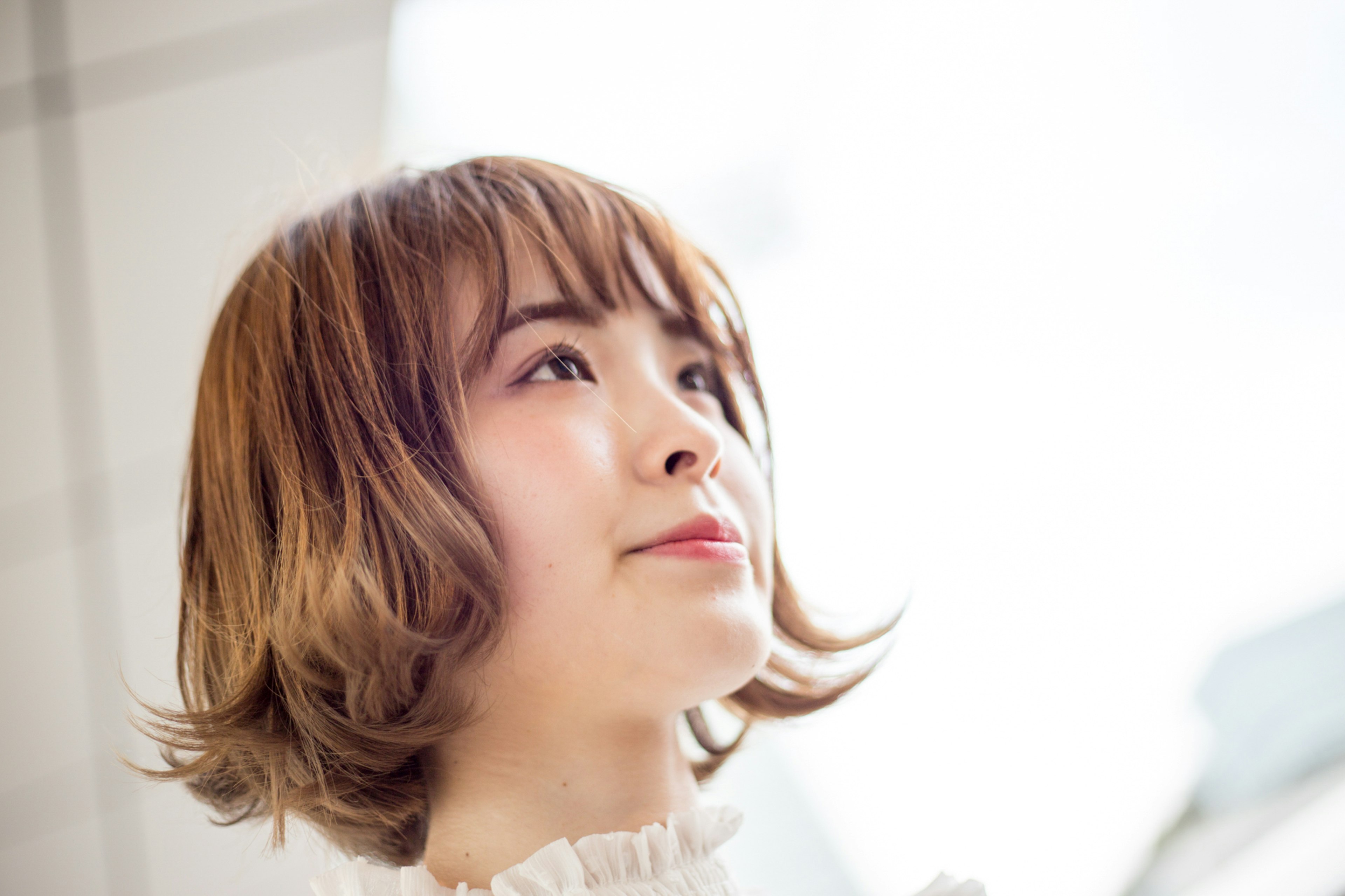 Young woman smiling towards a bright background