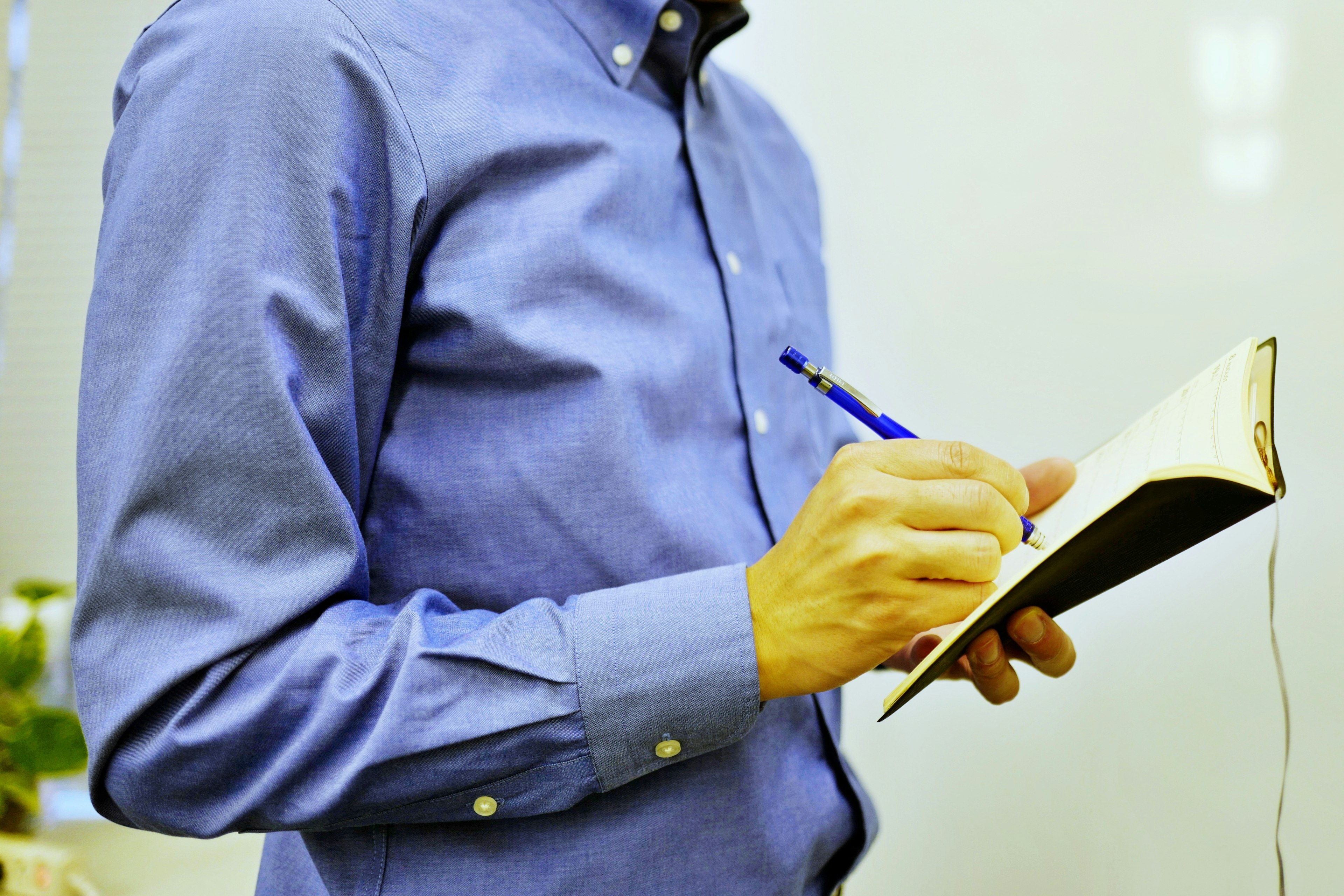 A man in a blue shirt writing notes in a notebook