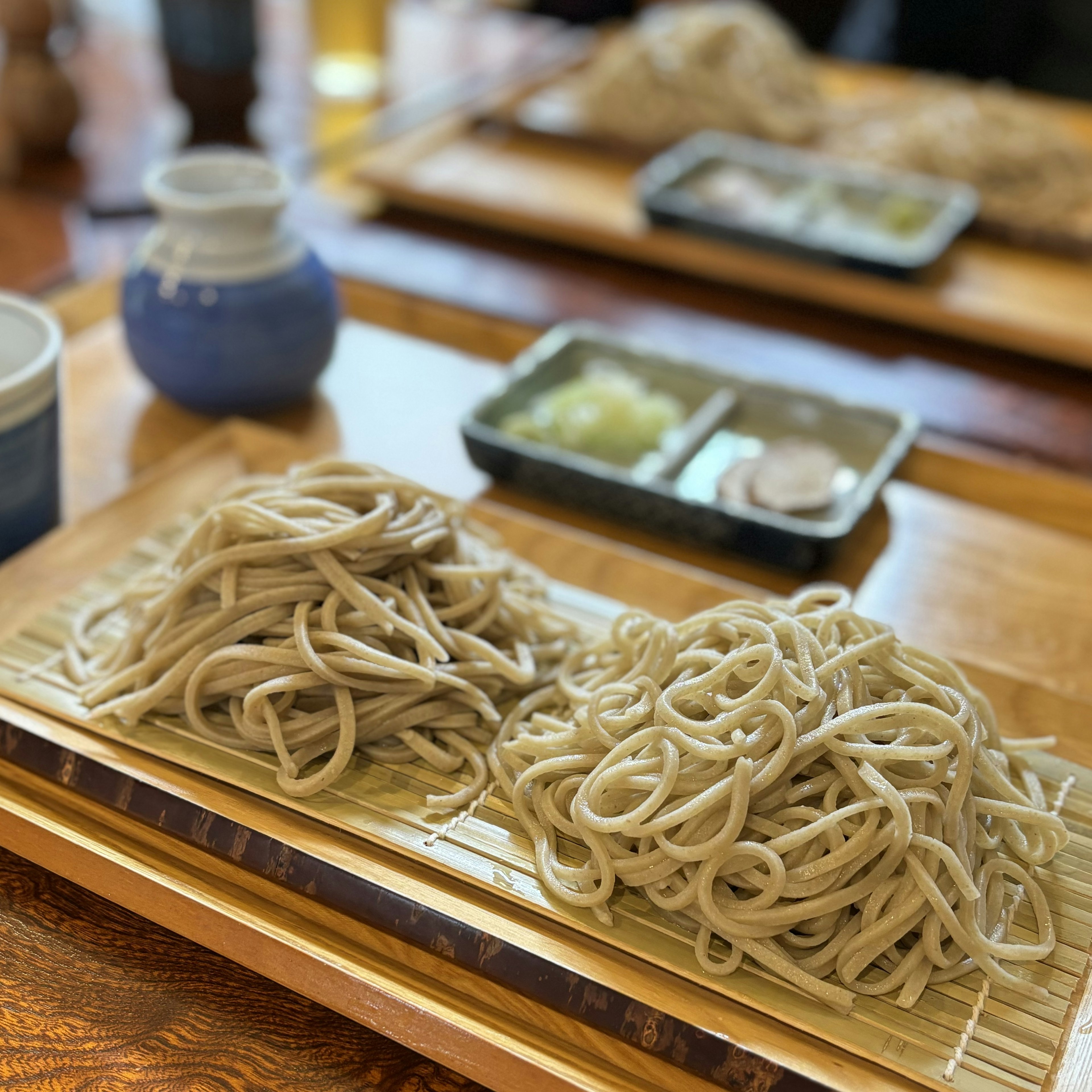 Une photo de nouilles soba japonaises servies en deux portions sur un plateau en bambou