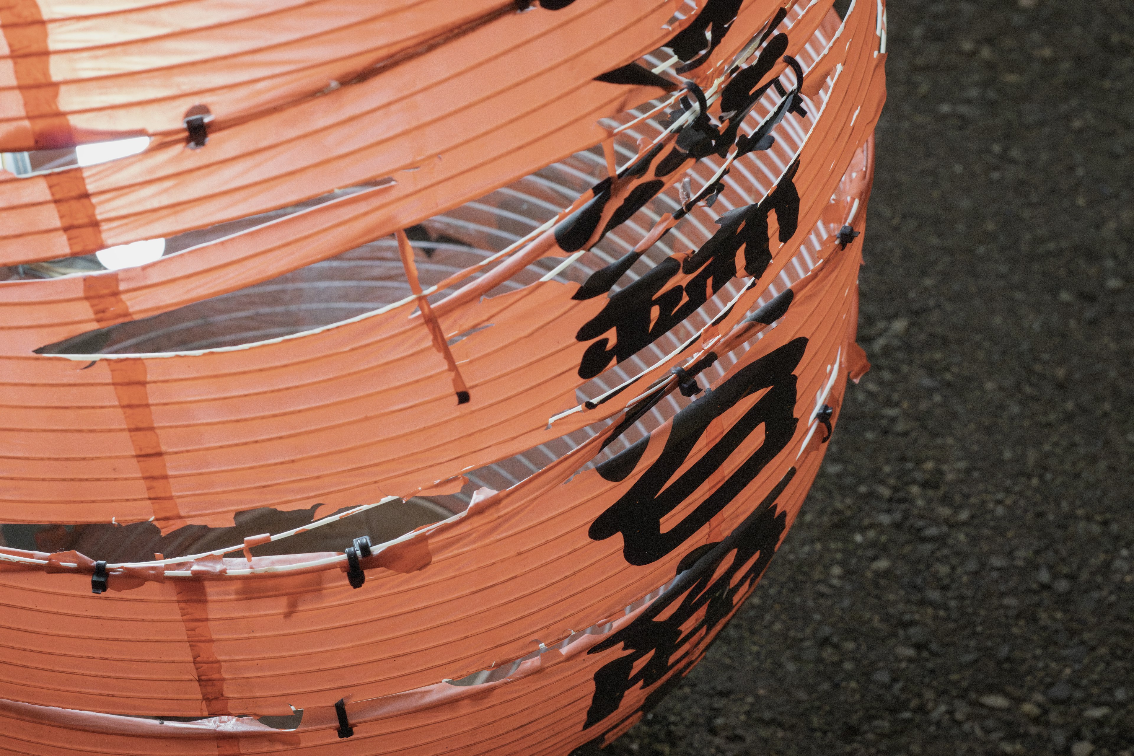 Close-up of an orange lantern featuring black Japanese characters