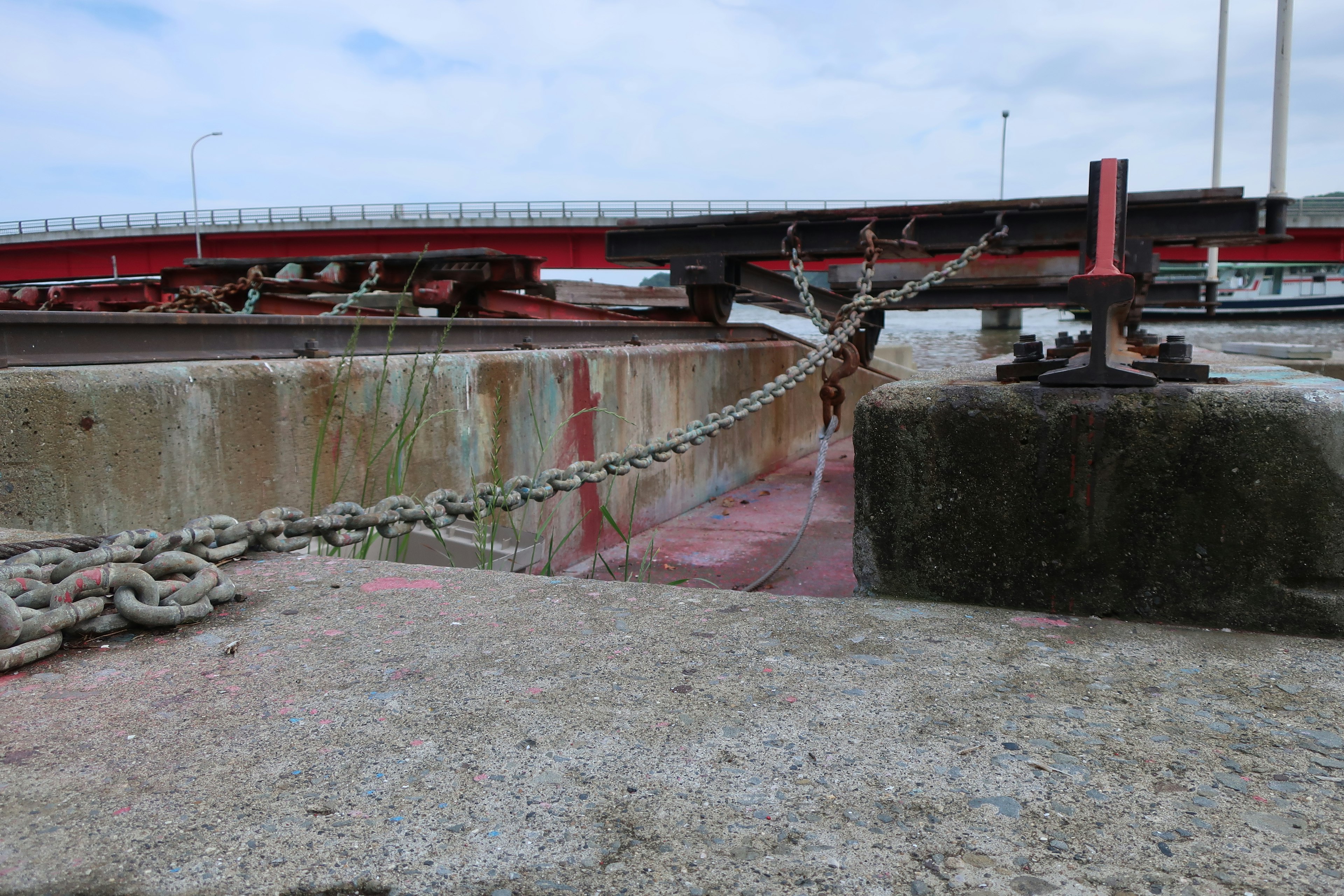 View of a harbor with a red bridge and chain