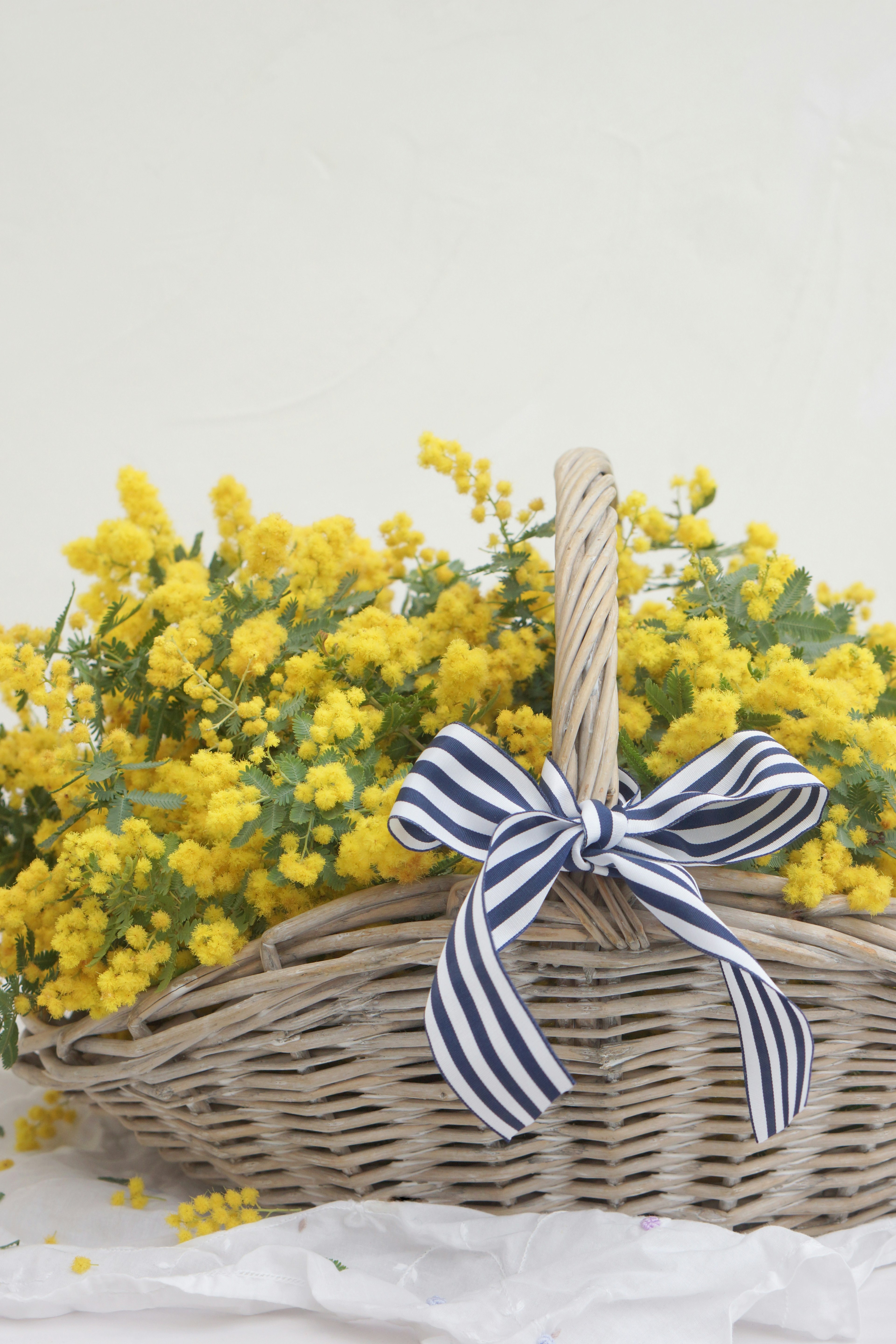 Cesta de mimbre llena de flores amarillas brillantes con una cinta a rayas