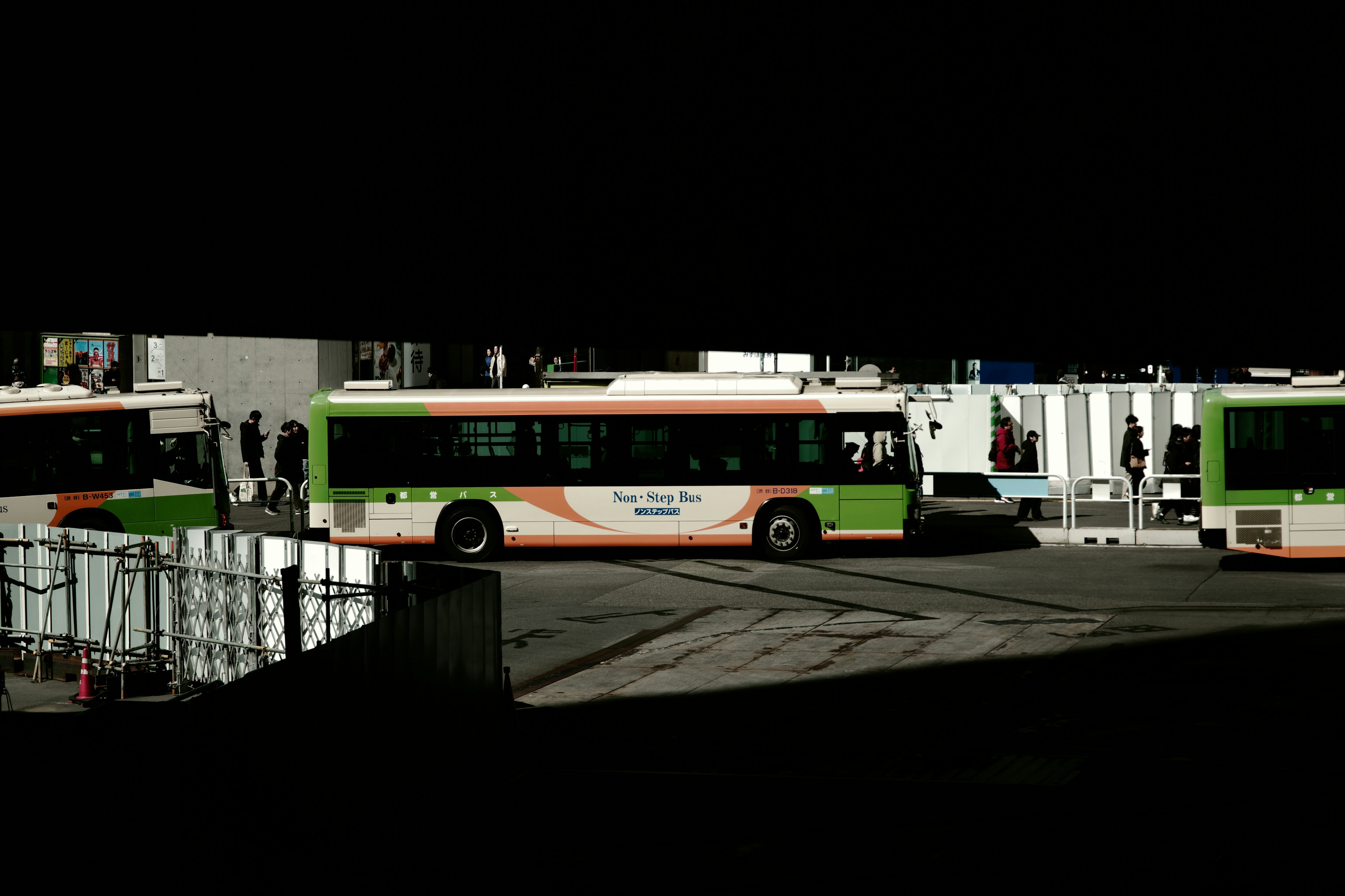 Buses en un centro de transporte con colores verde y naranja