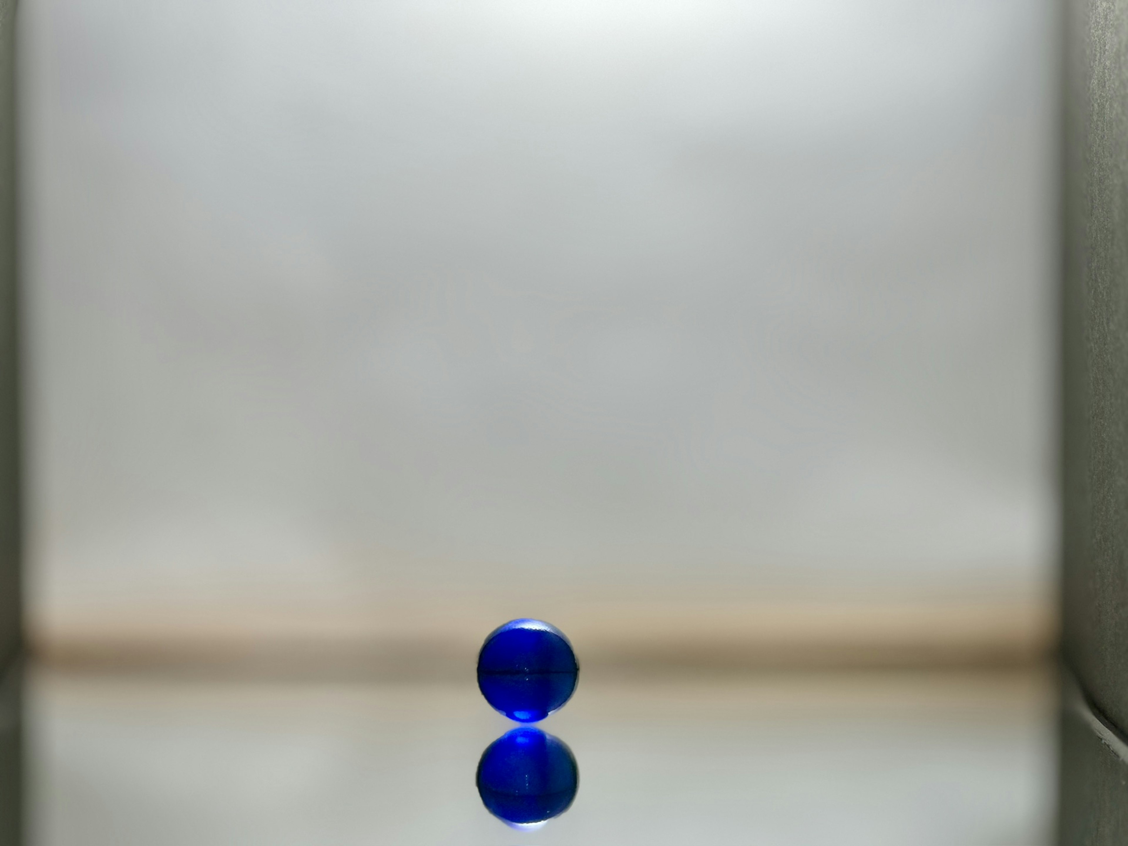 A blue glass sphere reflecting on a simple background