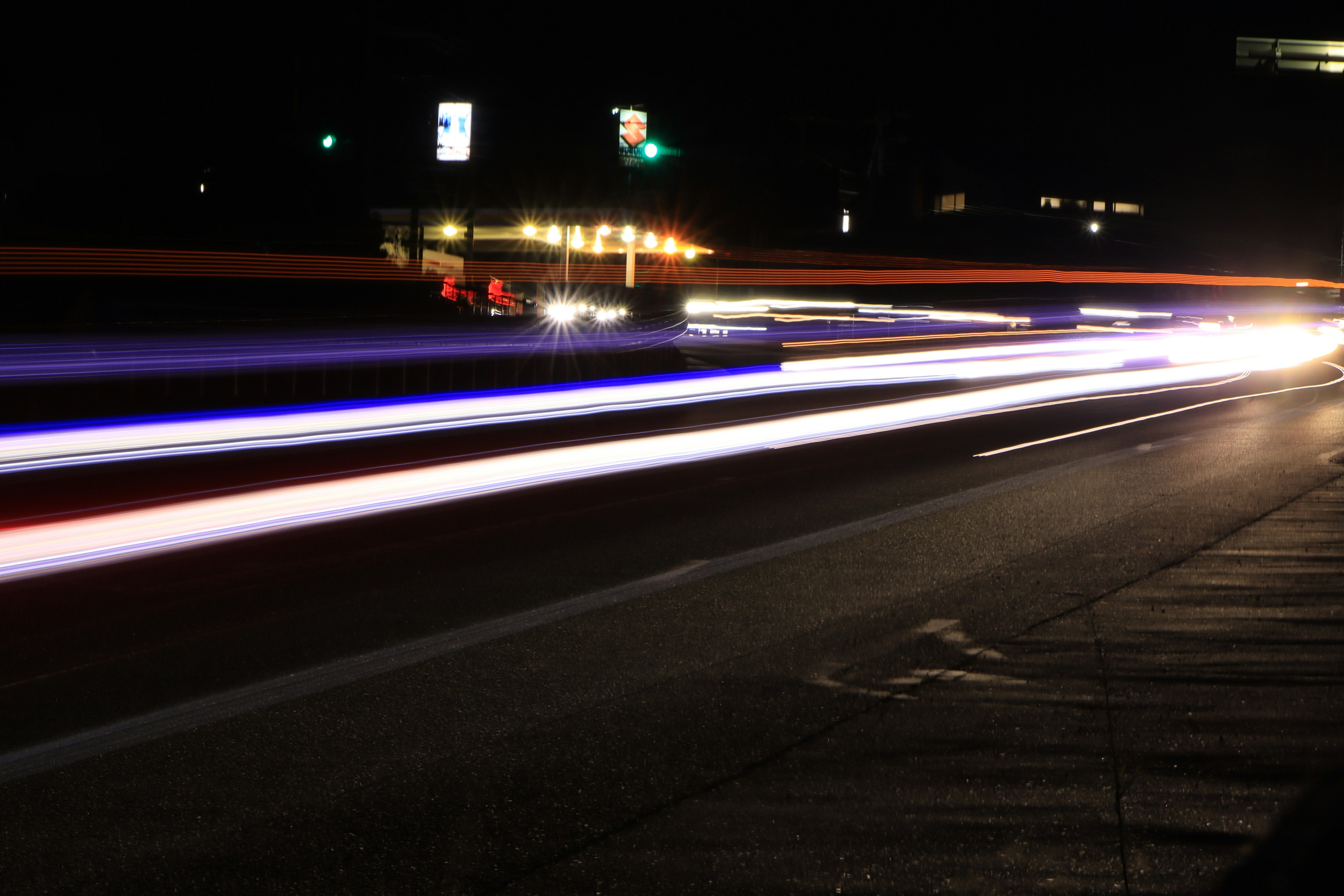 Photo des traînées lumineuses des voitures sur une route la nuit