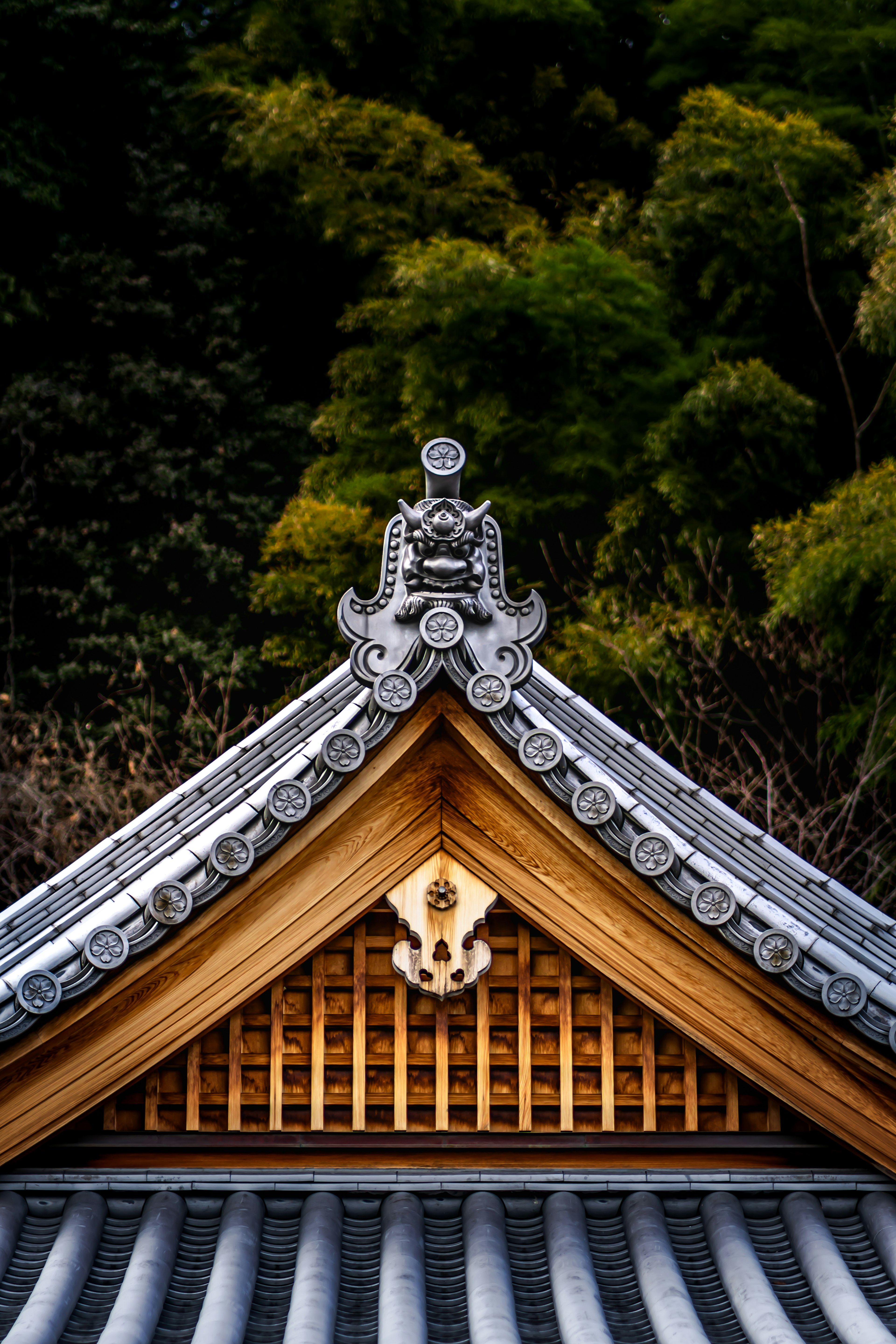 Diseño de techo japonés tradicional con decoraciones de madera y piedra sobre un fondo verde