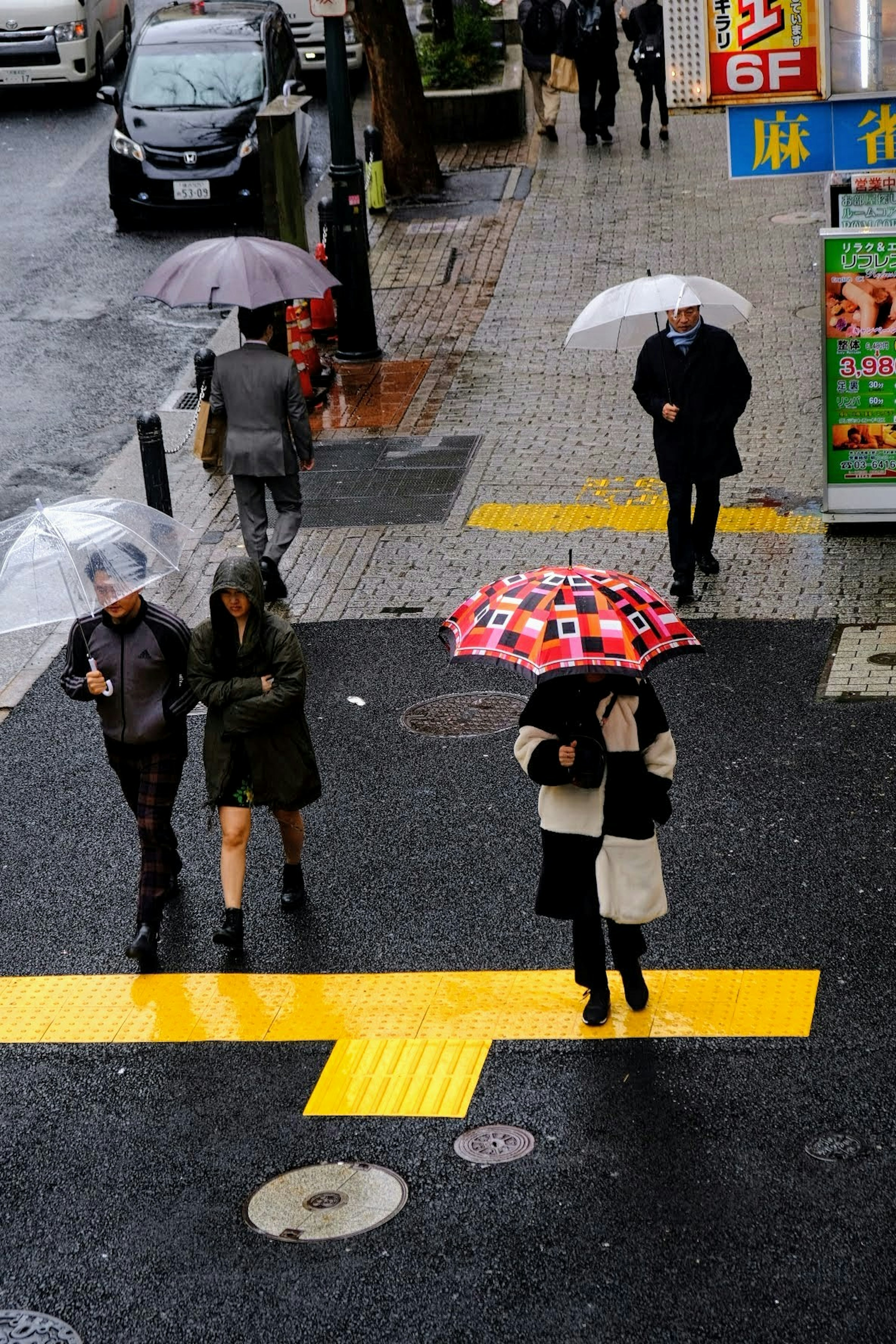 Persone che attraversano la strada con ombrelli sotto la pioggia