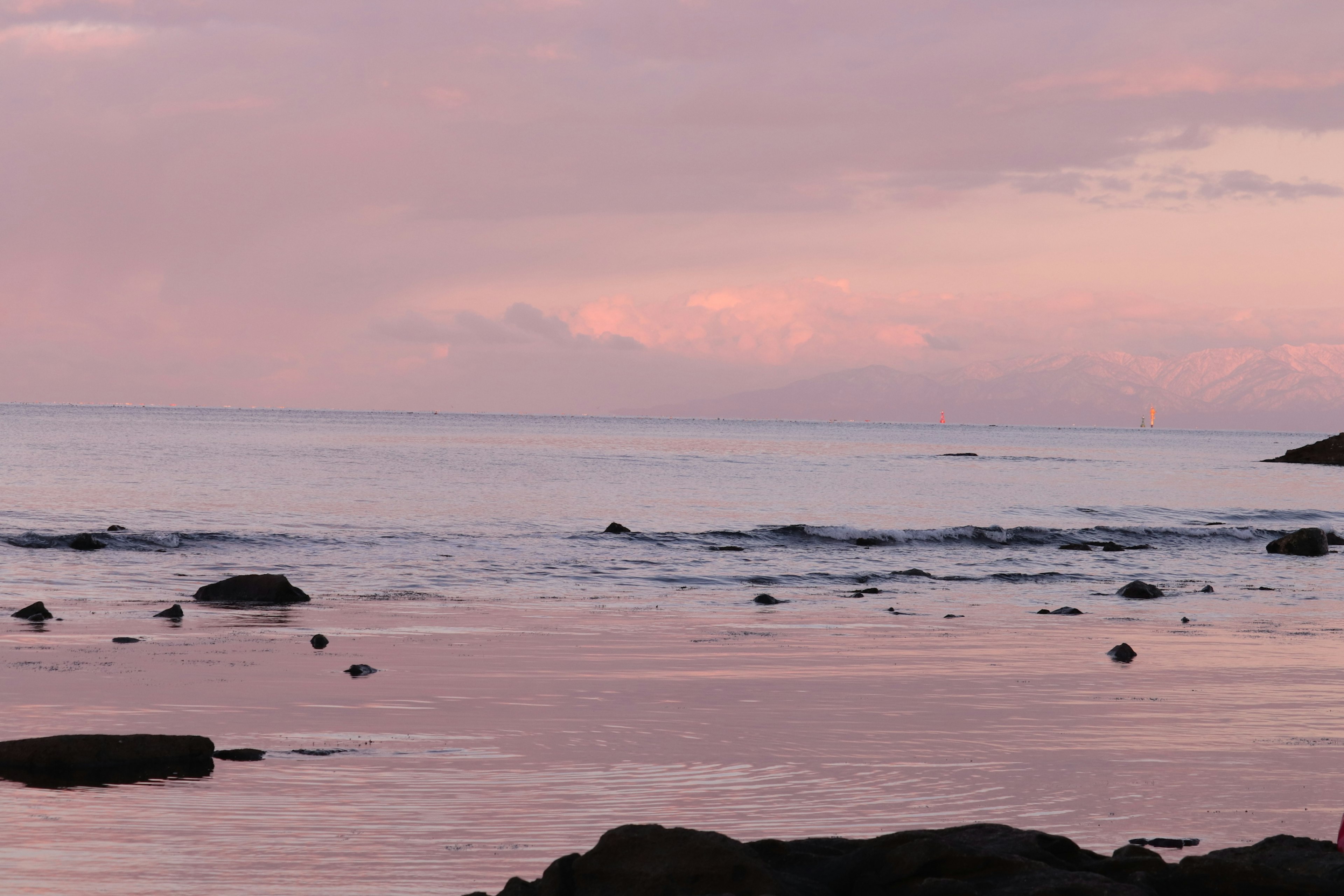 Laut tenang dengan langit merah muda saat matahari terbenam