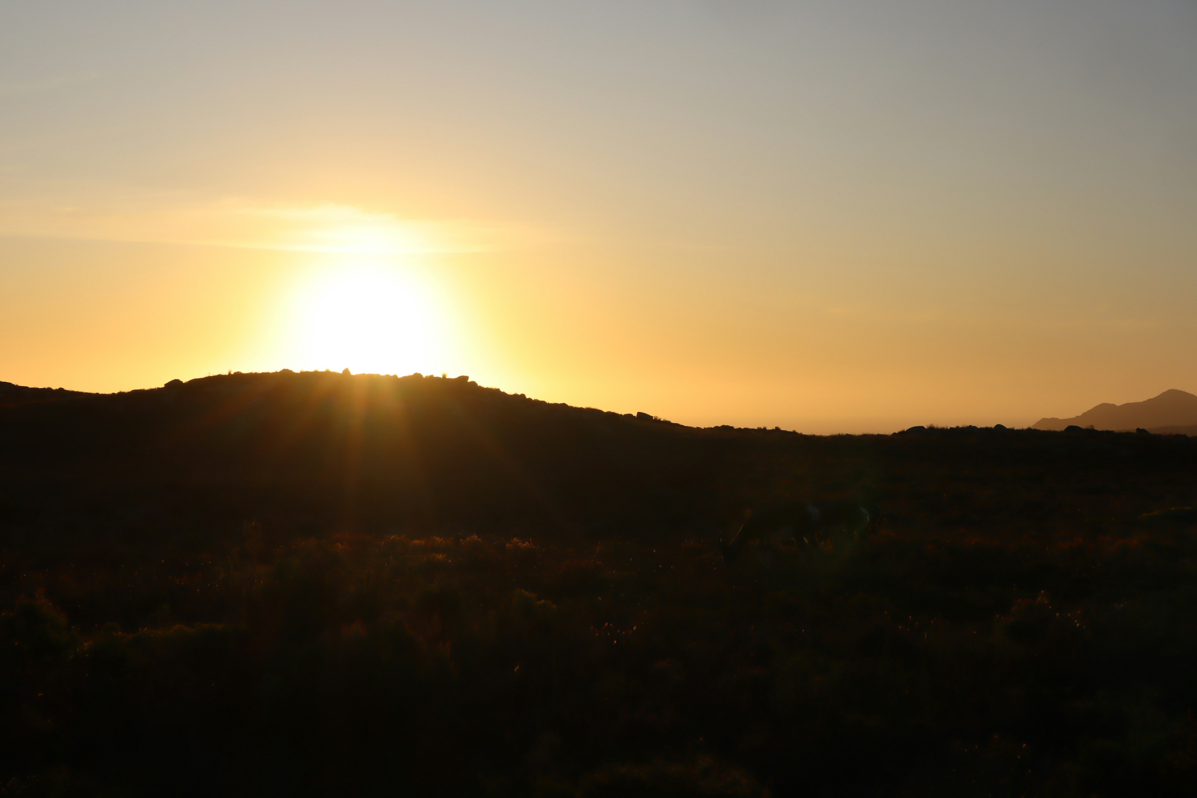 Silueta de colinas al amanecer con luz cálida