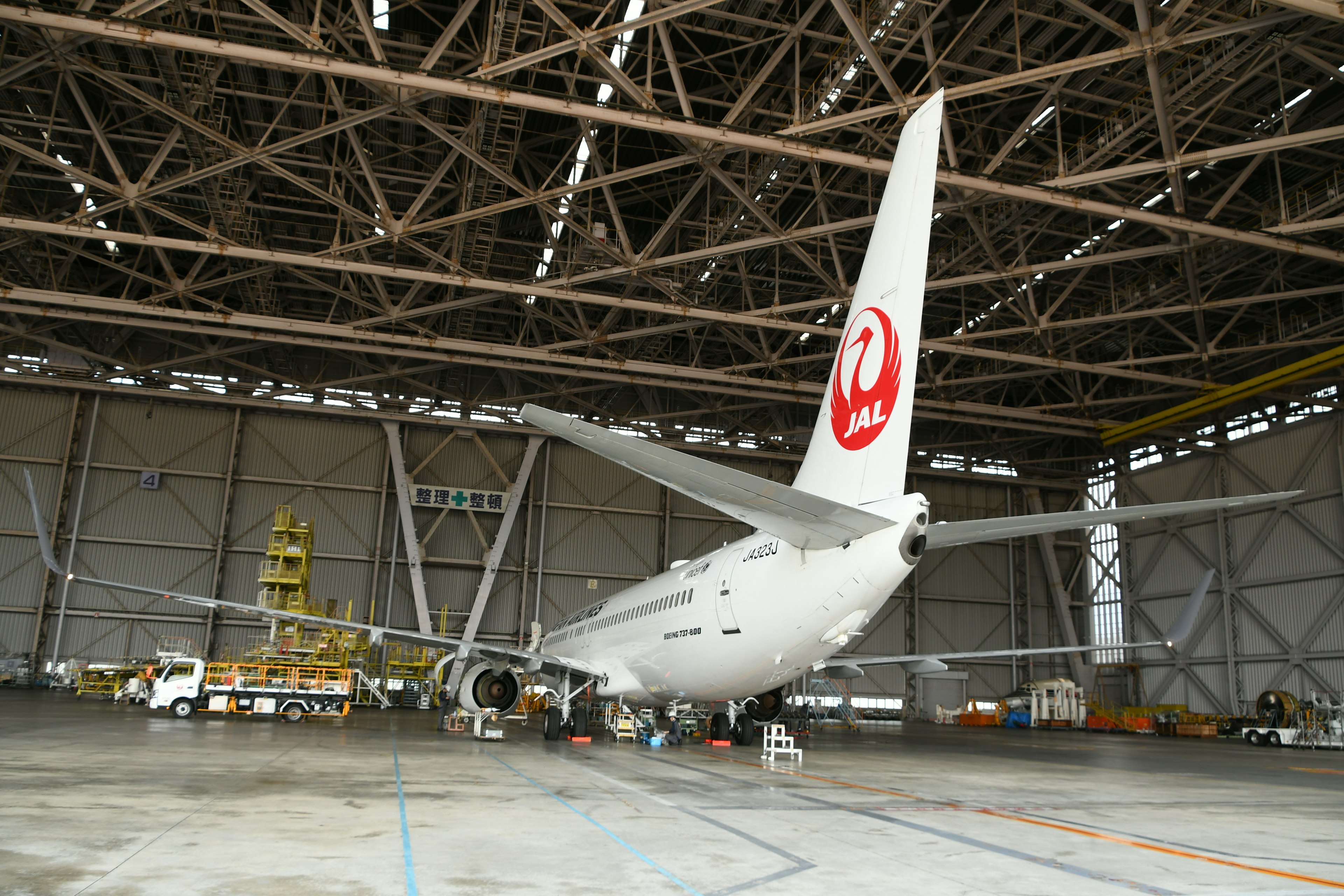 Interno di un hangar per aerei con un aereo in manutenzione che mostra il logo di una compagnia aerea