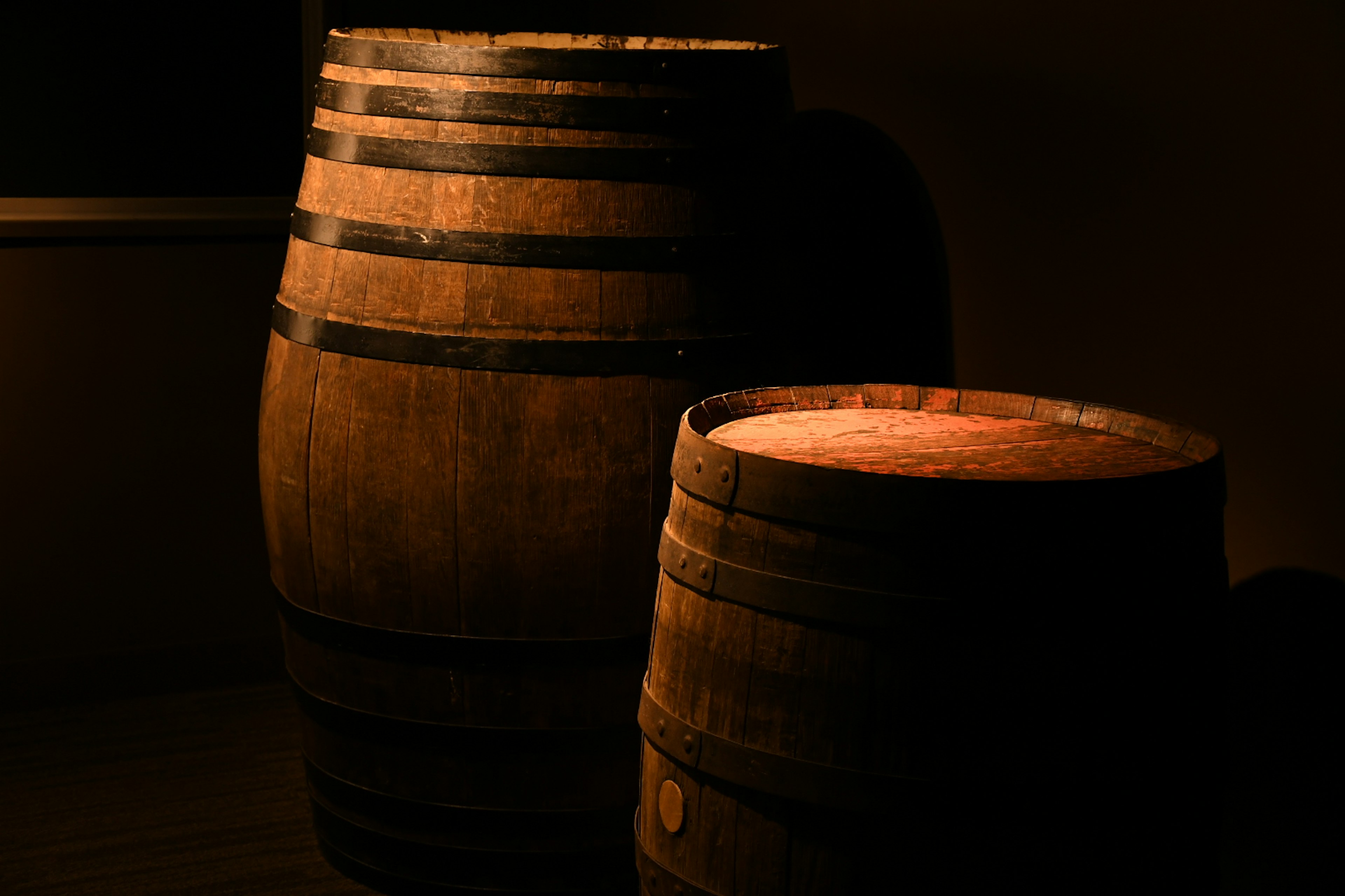 Two wooden barrels illuminated against a dark background