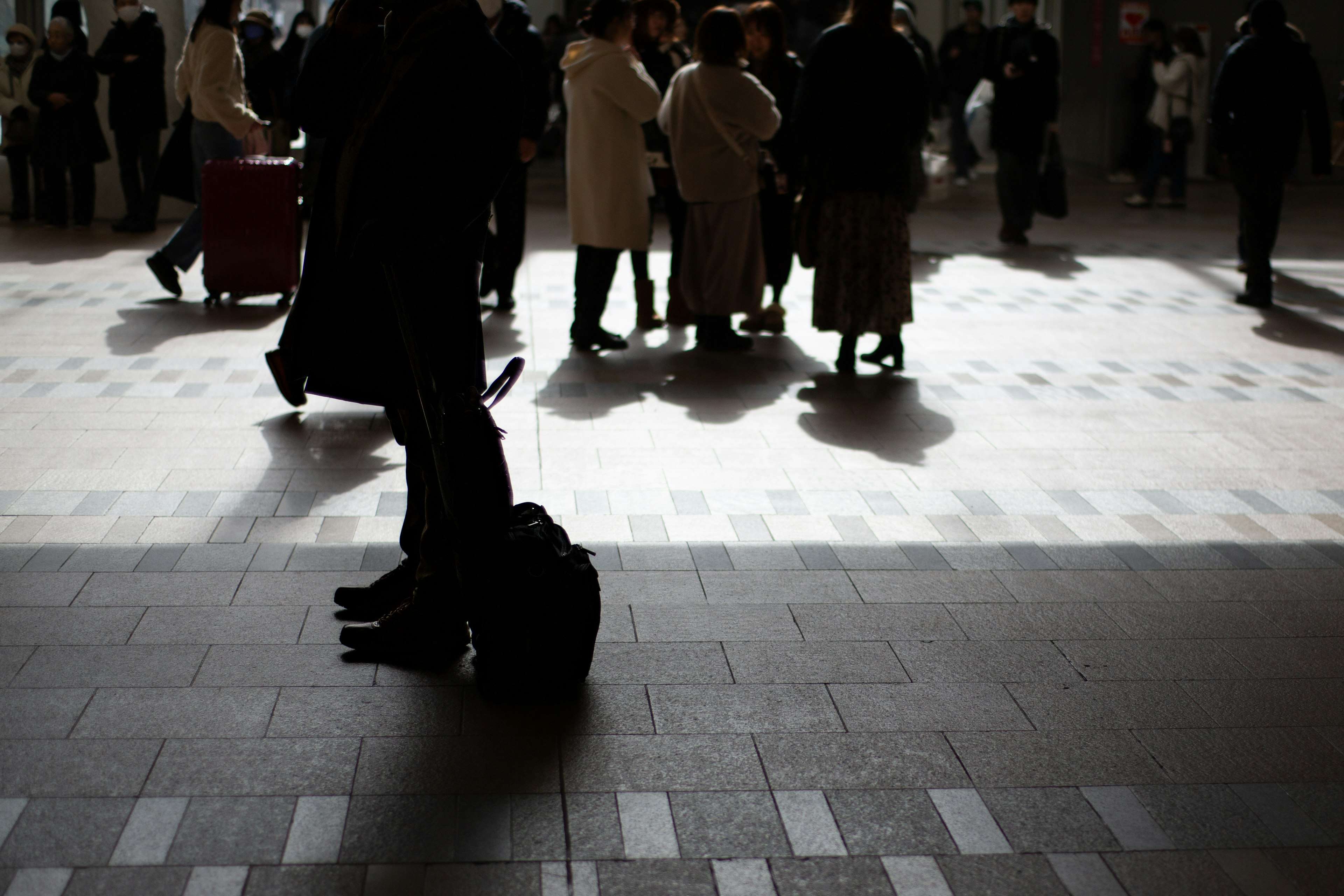 Silhouette von Menschen, die sich in einem Bahnhof mit Licht und Schatten versammeln