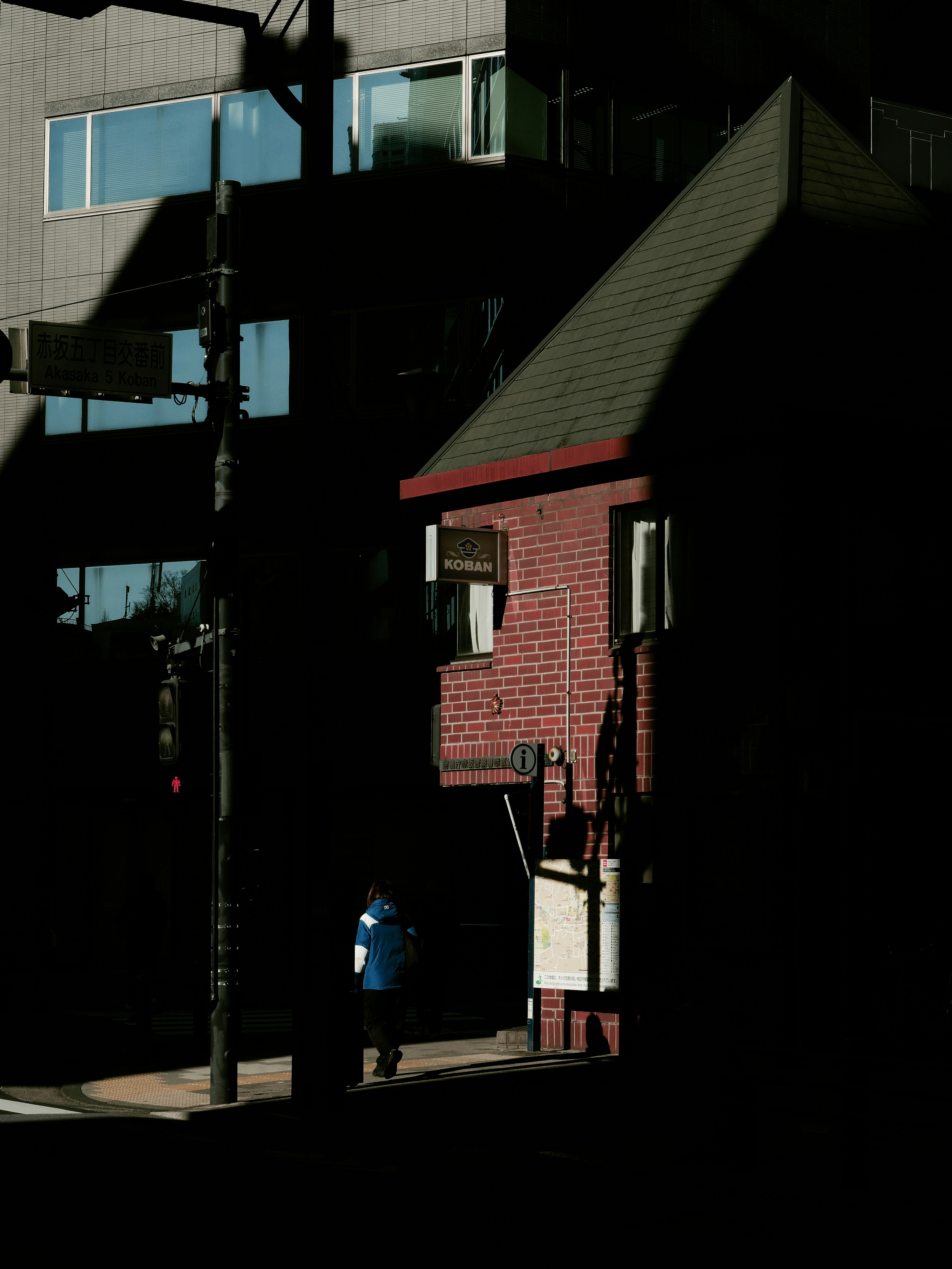 Edificio de ladrillo con techo rojo y una persona de pie en las sombras