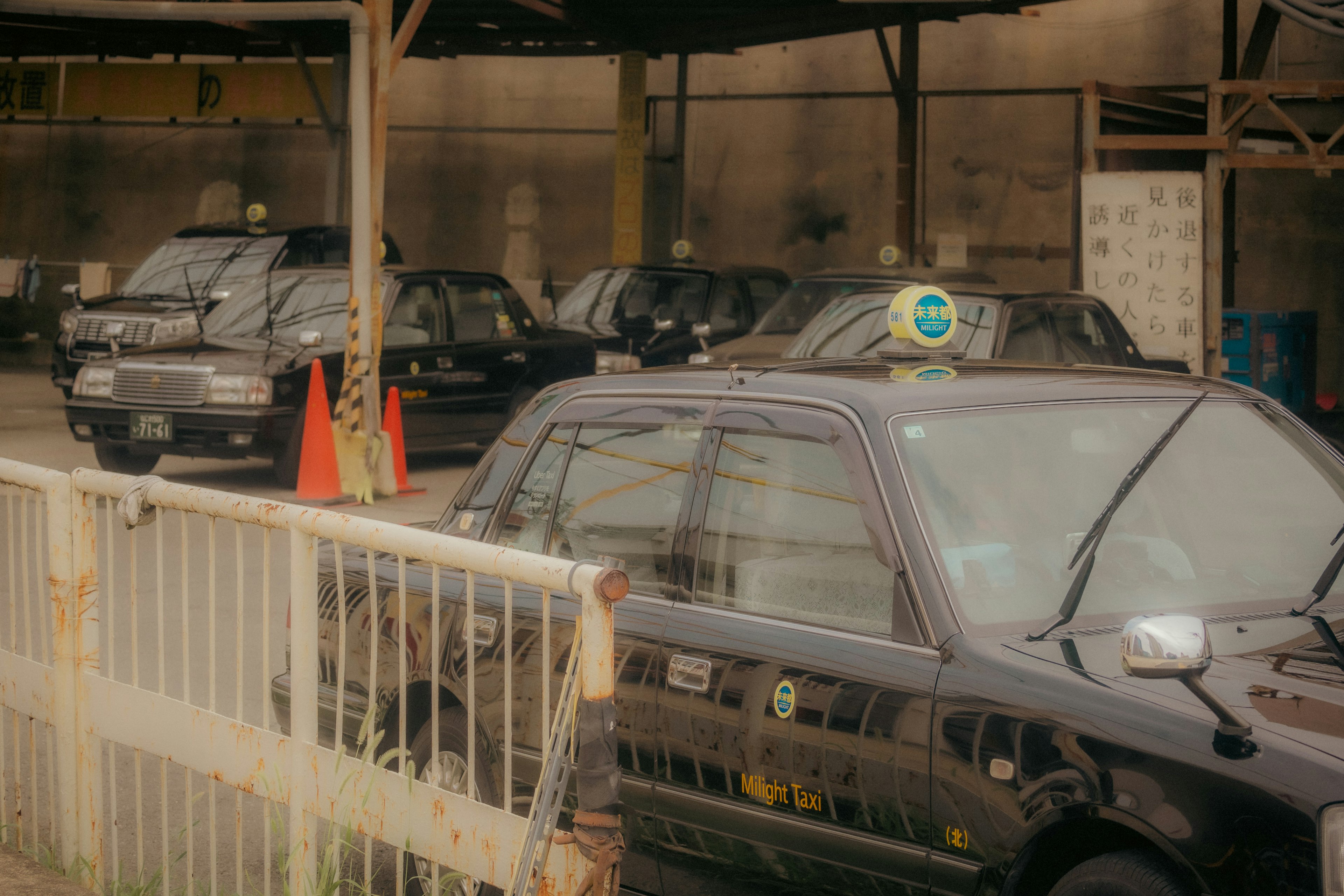 Interior of a taxi depot with parked black taxis and orange cones