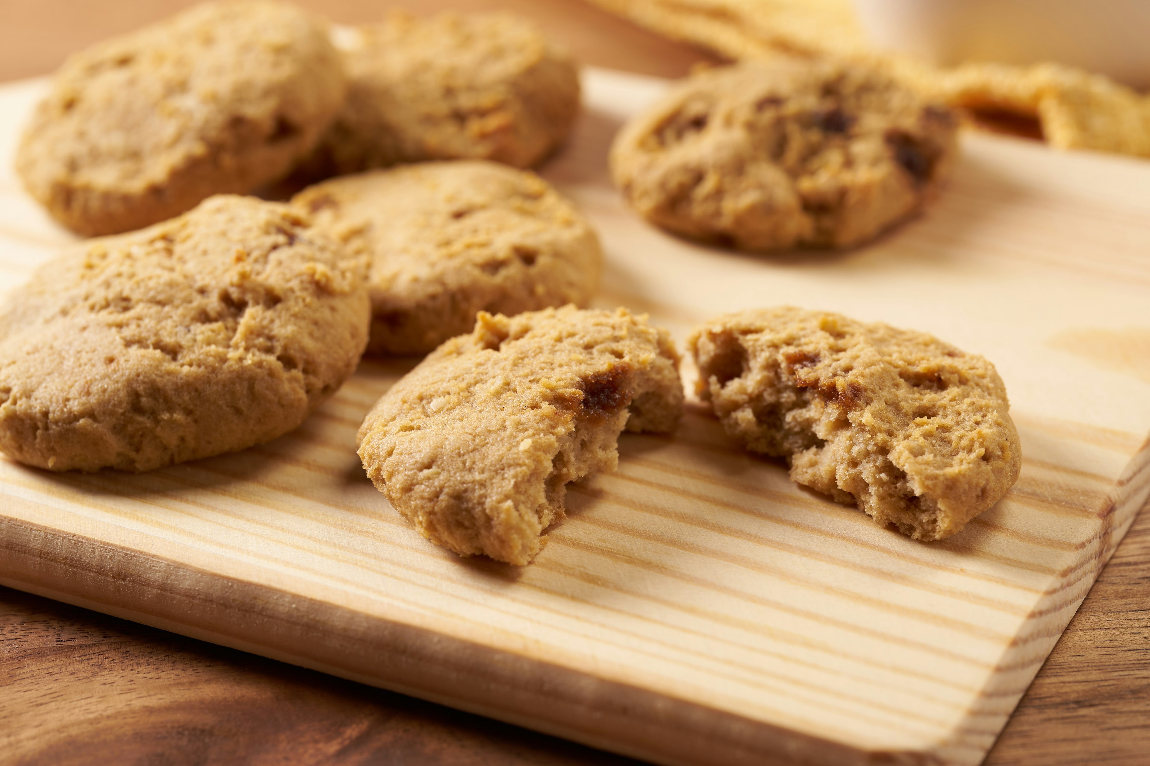 Des biscuits sur une planche en bois avec un biscuit partiellement mordu montrant une texture moelleuse