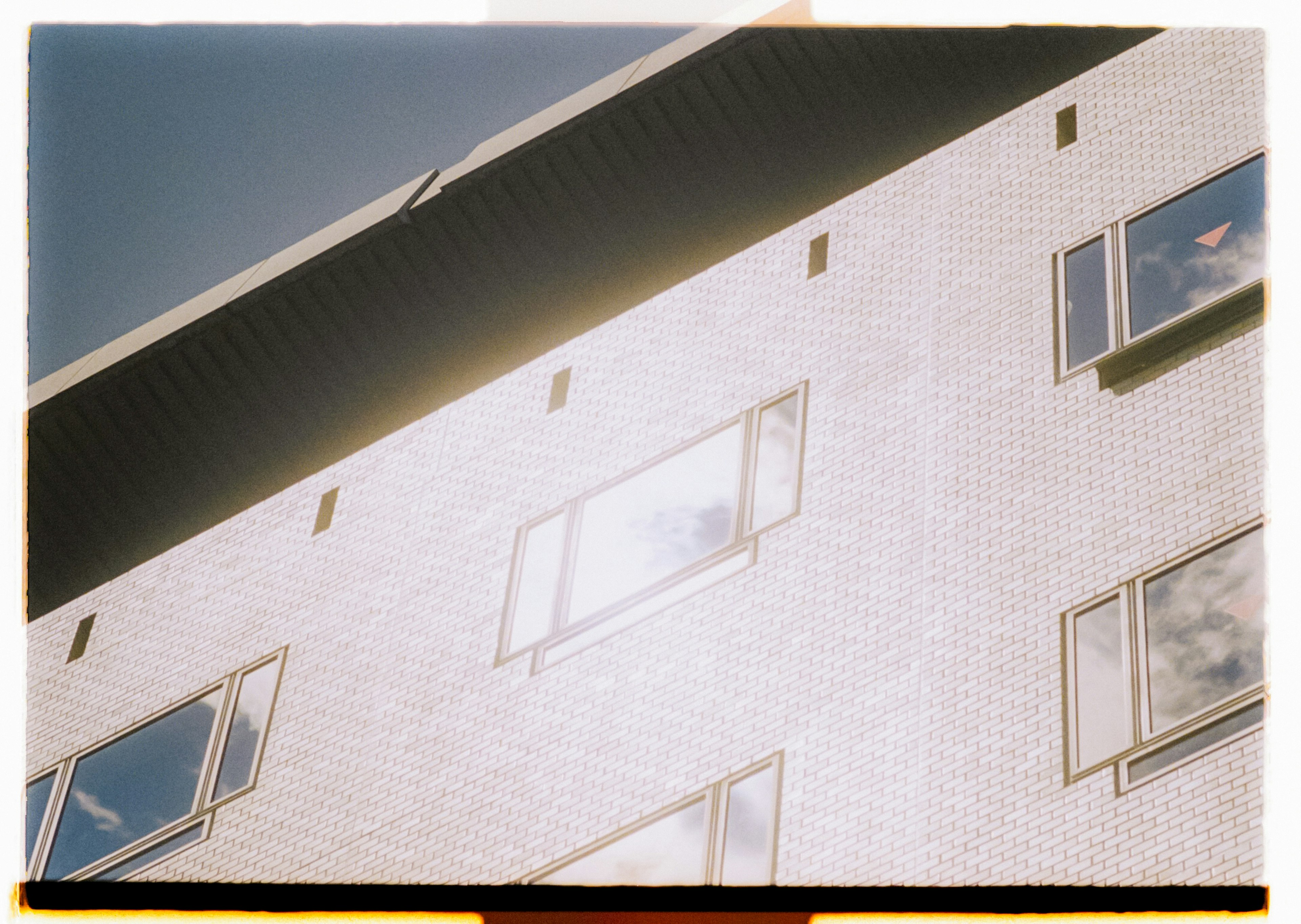 Partie d'un bâtiment en briques blanches avec des fenêtres visibles