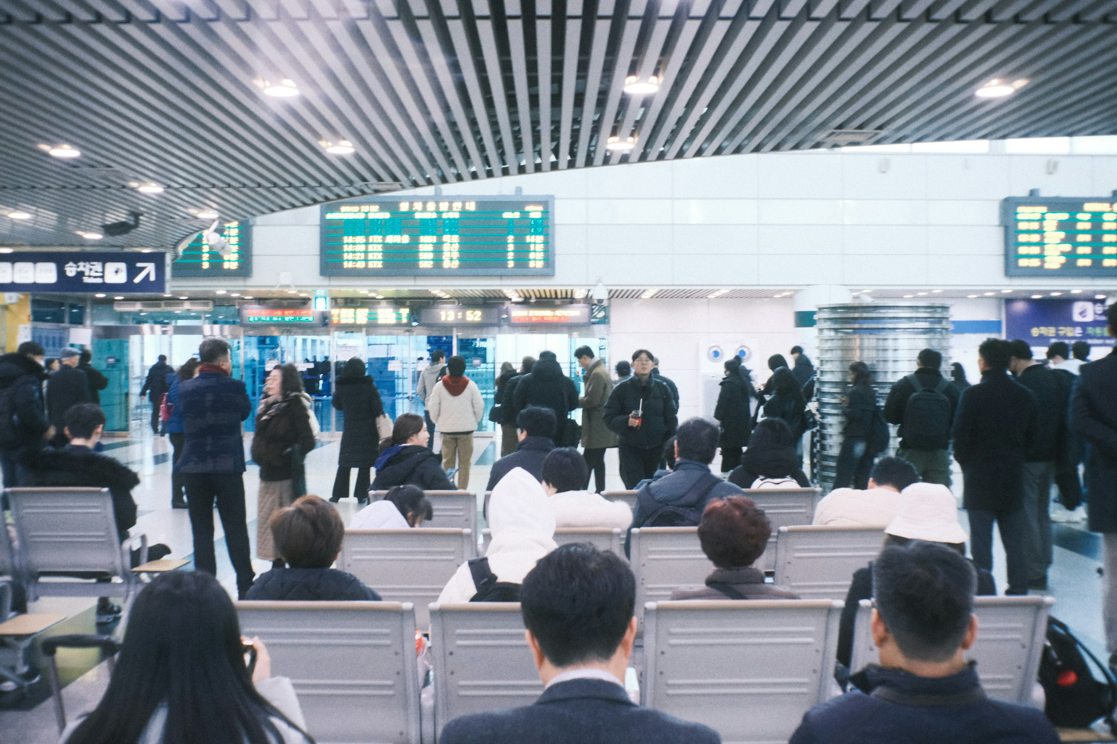 空港の待合室にいる乗客たちと出発・到着ボード