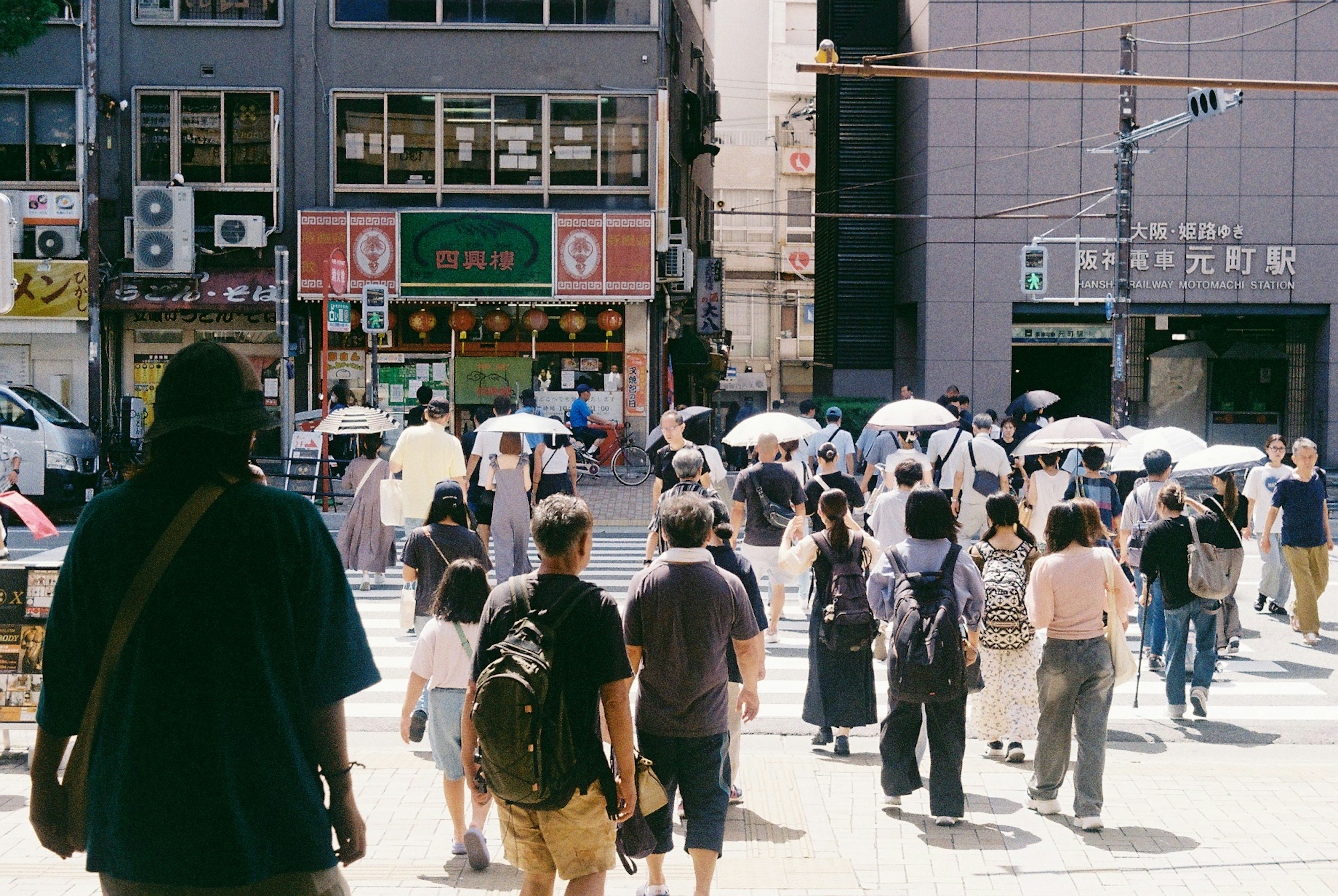 Busy street scene with people walking under umbrellas