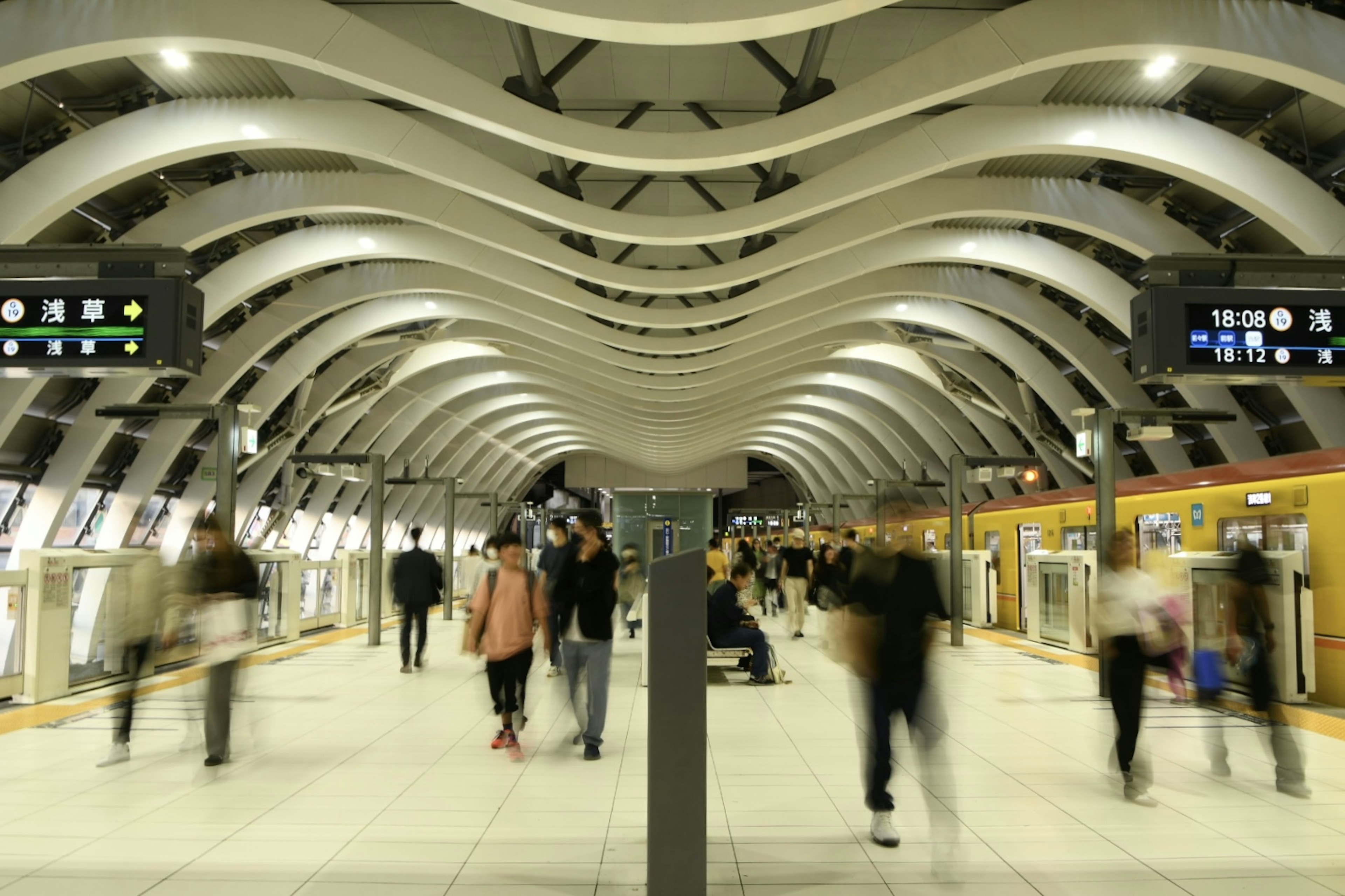 Modern train station interior with people walking under a wavy ceiling and bright lights