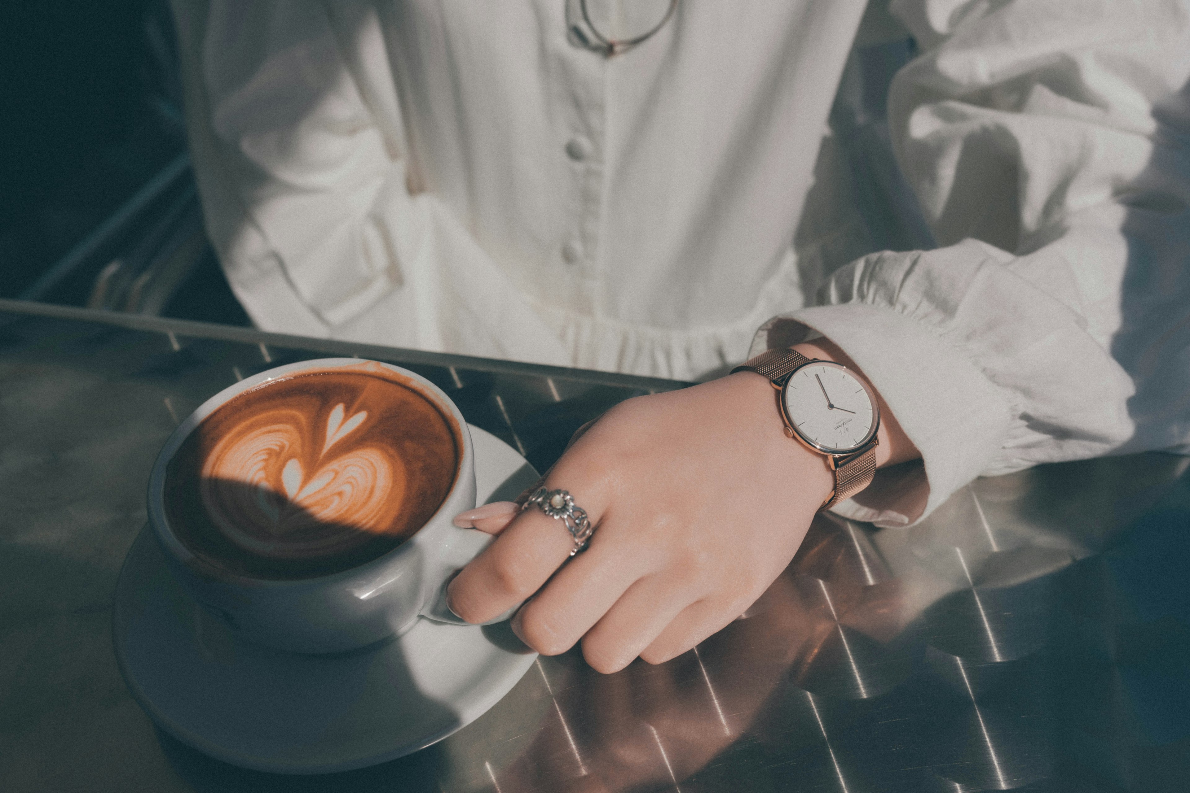 Hand holding a cup of latte with a watch on the wrist