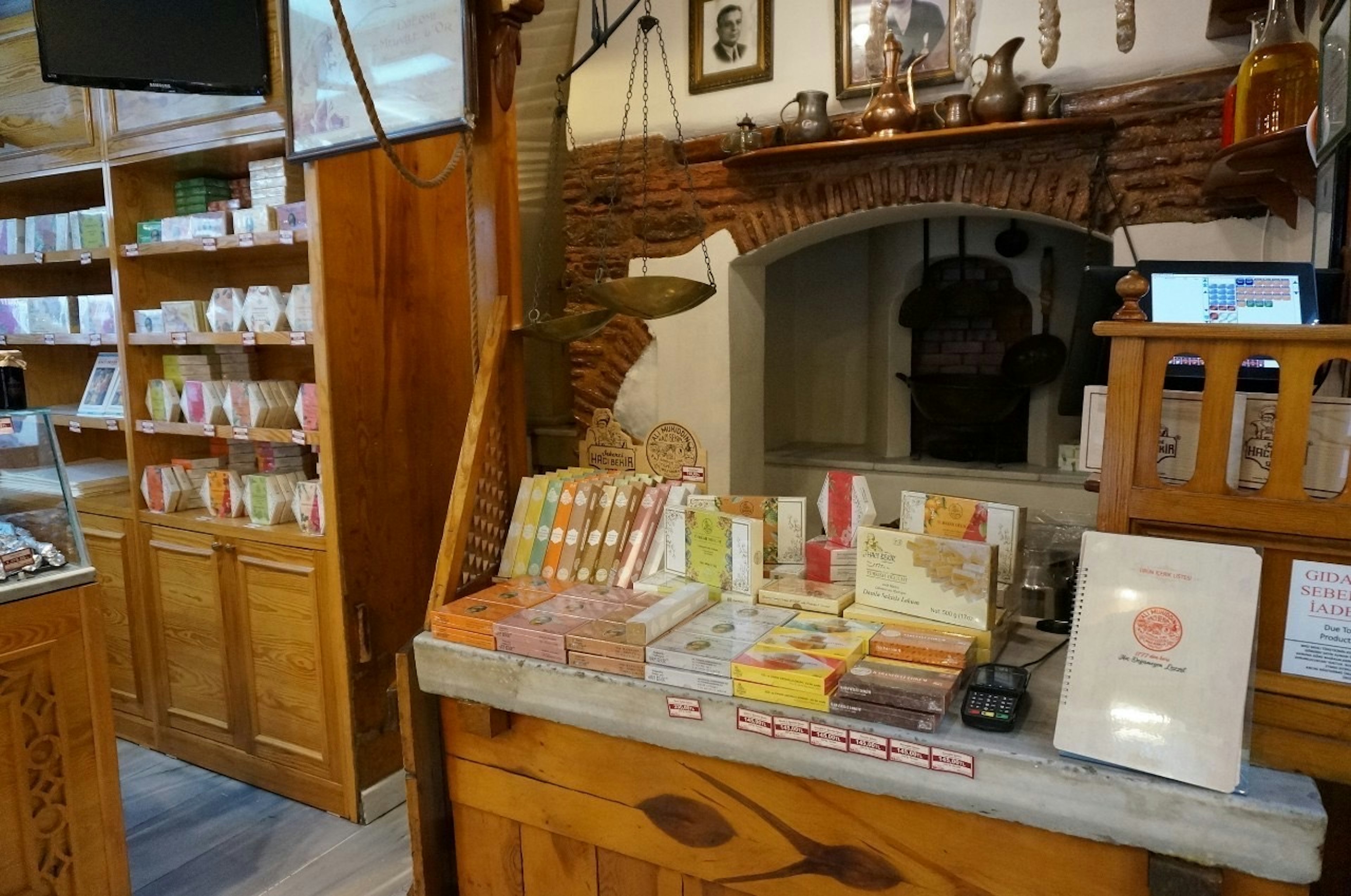 Interior de una tienda con un mostrador de madera mostrando productos y estantes al fondo