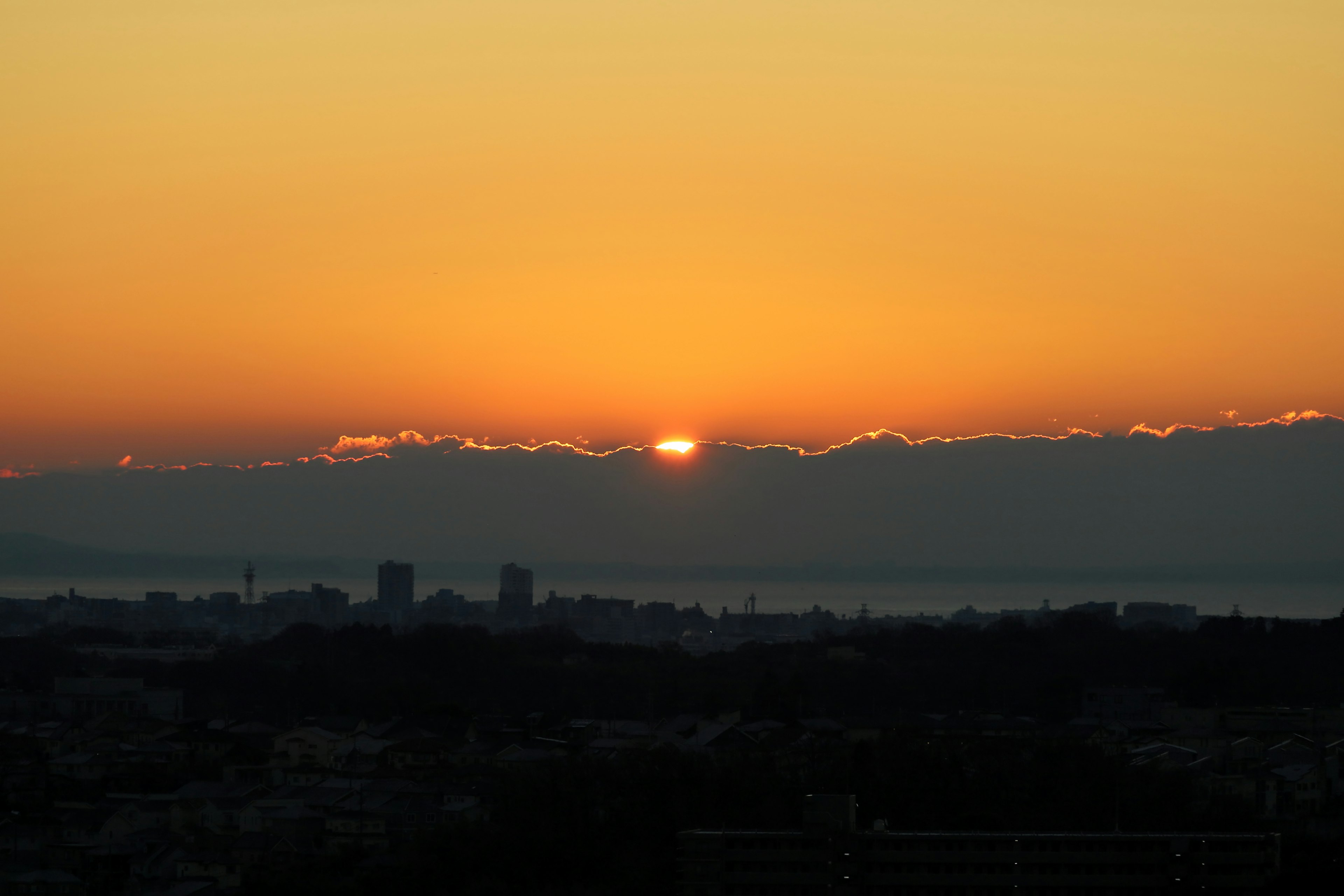 A beautiful sunset peeking through the mountains with a silhouette of the city