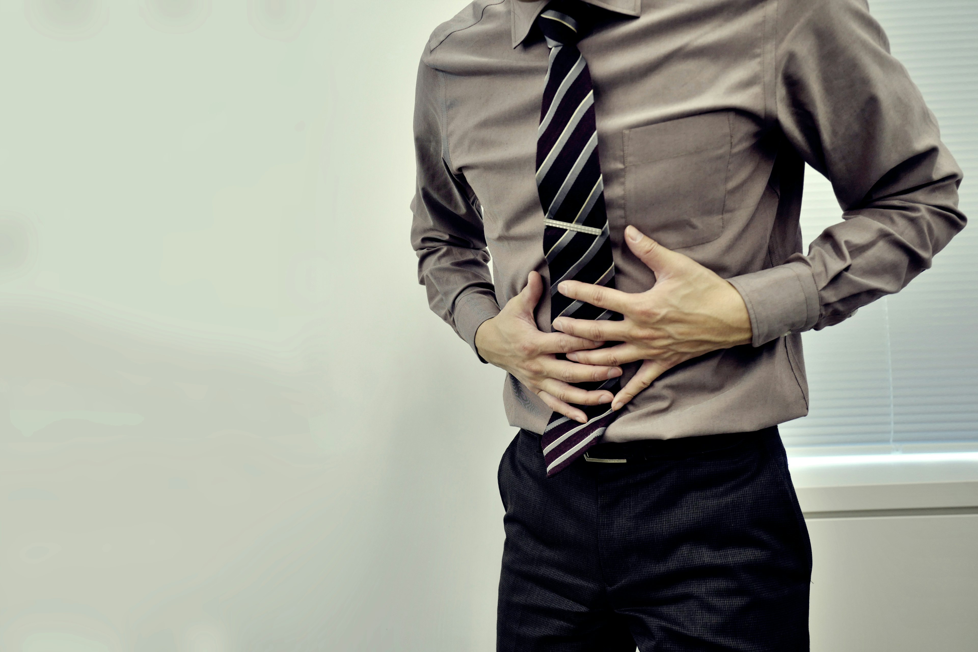 Man in business suit holding his stomach showing discomfort