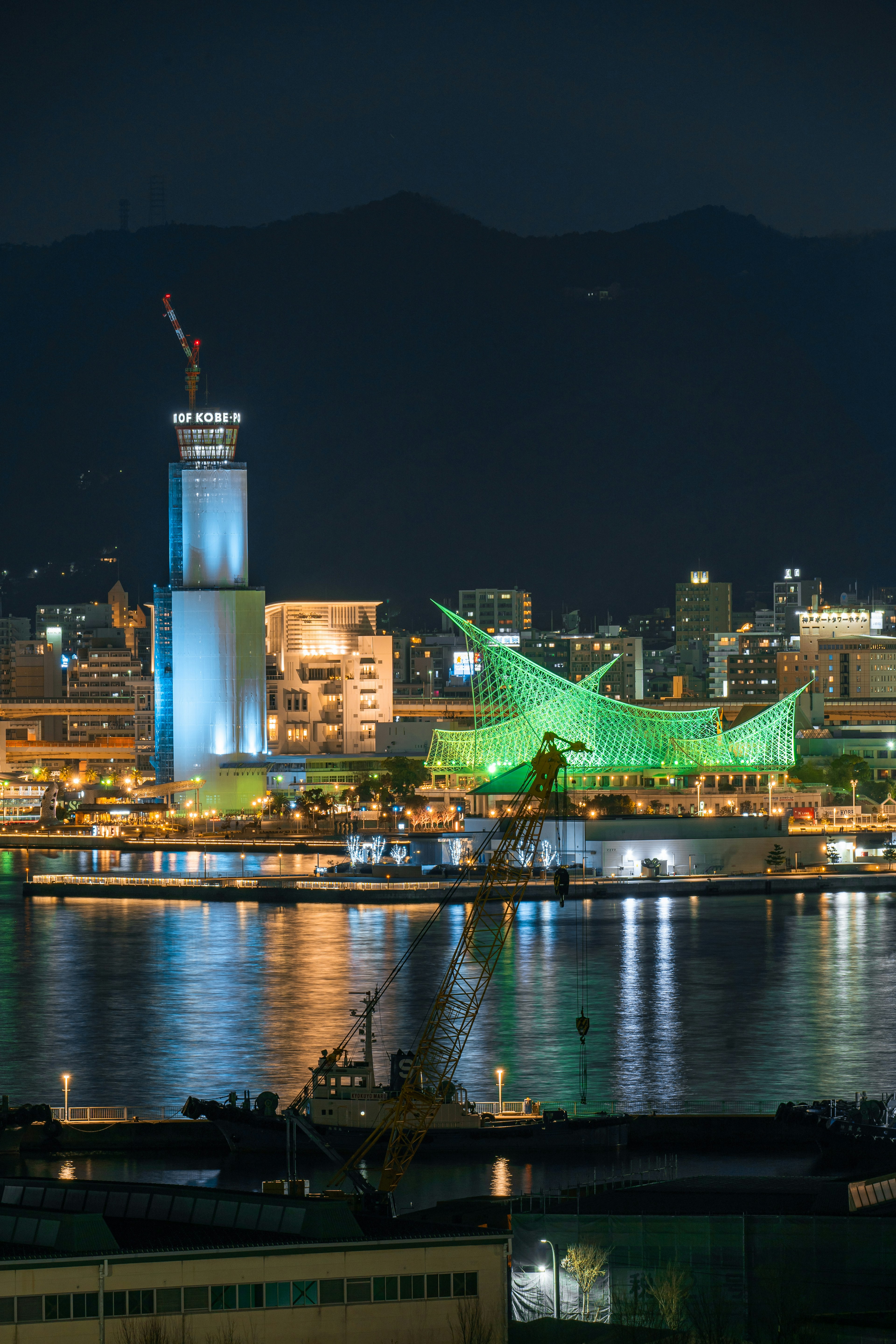 夜晚照亮的神戶港景觀，綠色建築和藍色塔