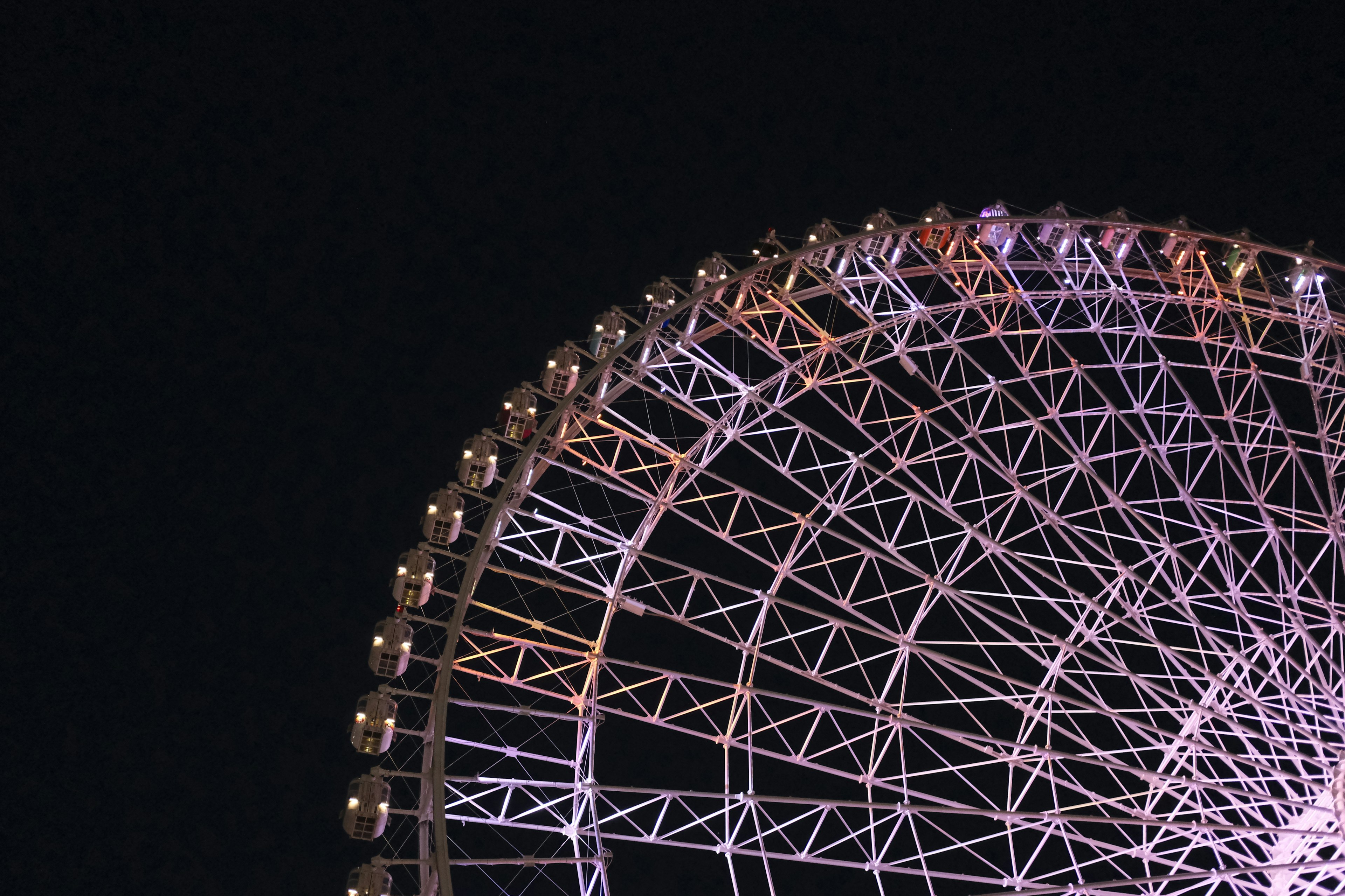 Part of a ferris wheel illuminated against the night sky