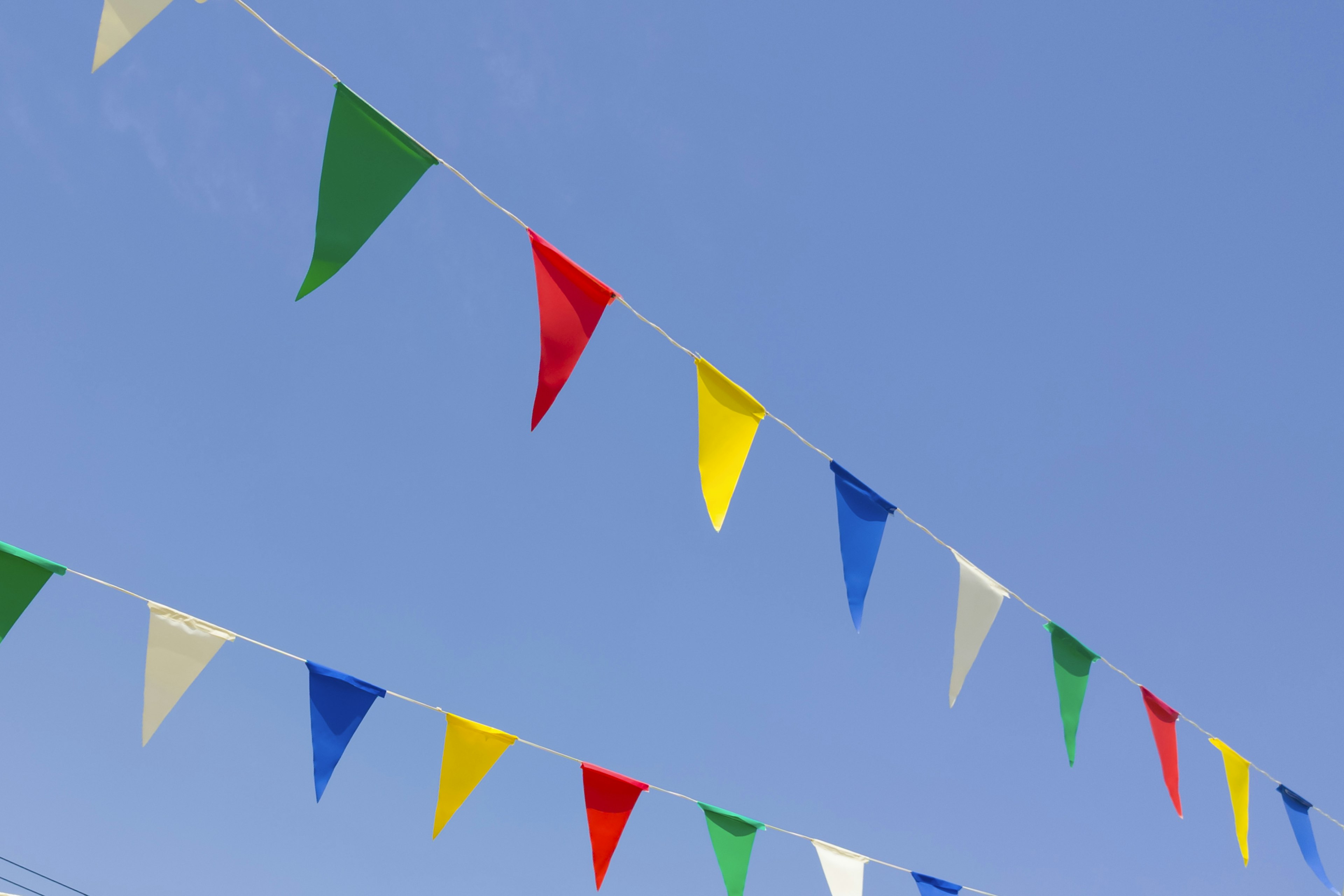 Bunte Fahnen hängen vor einem klaren blauen Himmel