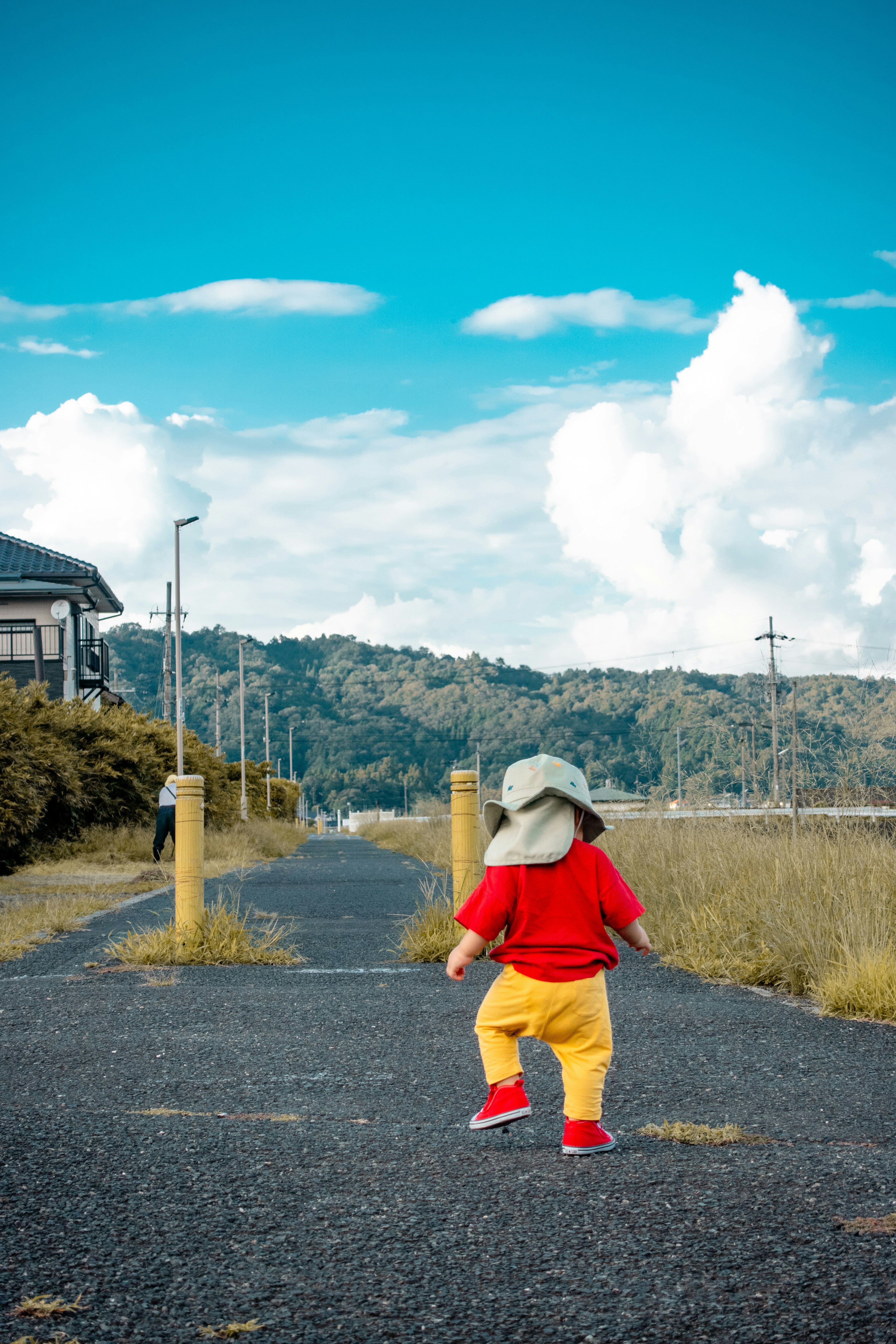 A child in a red shirt and yellow pants walking on a path