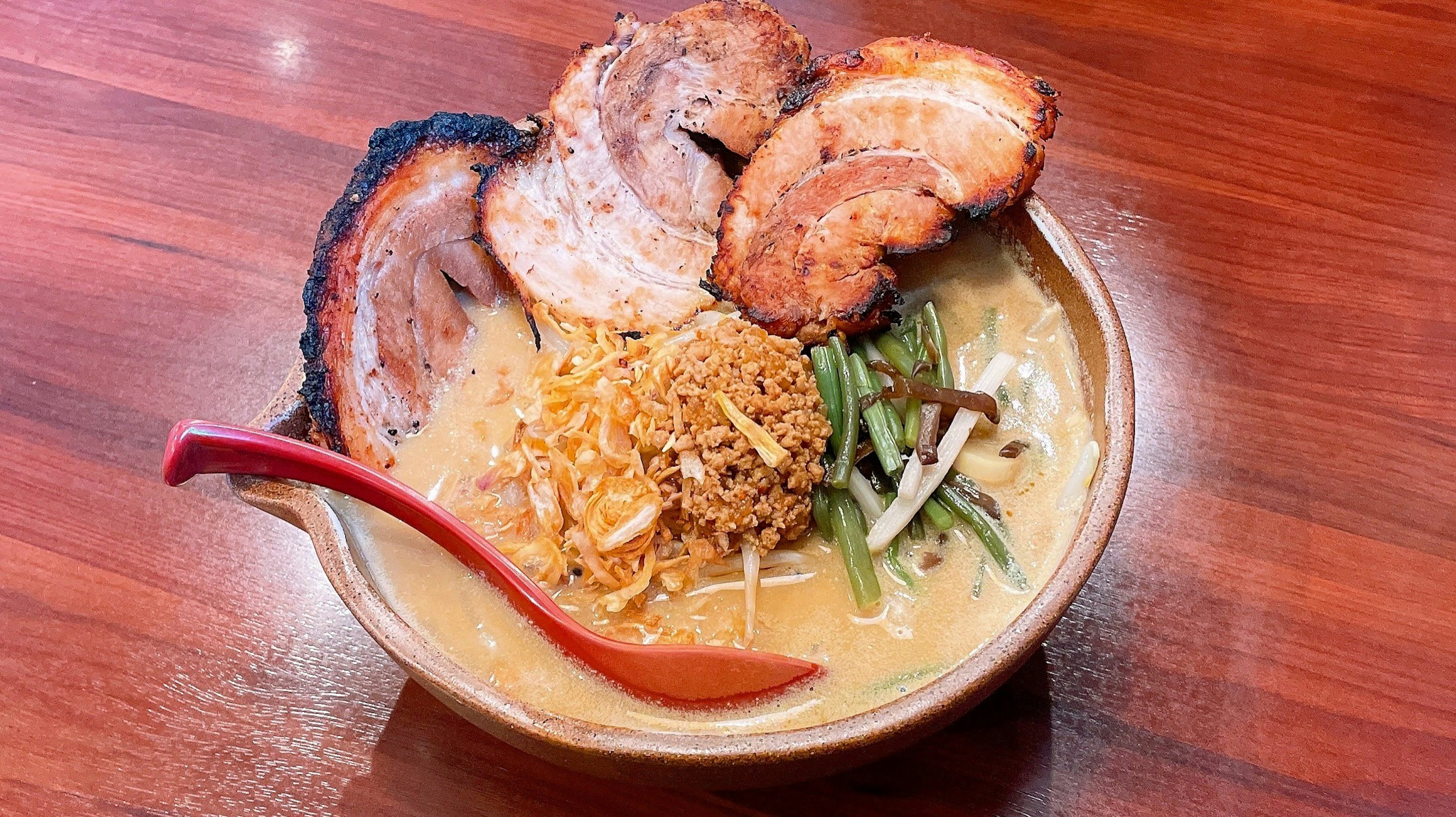 Delicious ramen bowl topped with slices of chashu and green onions