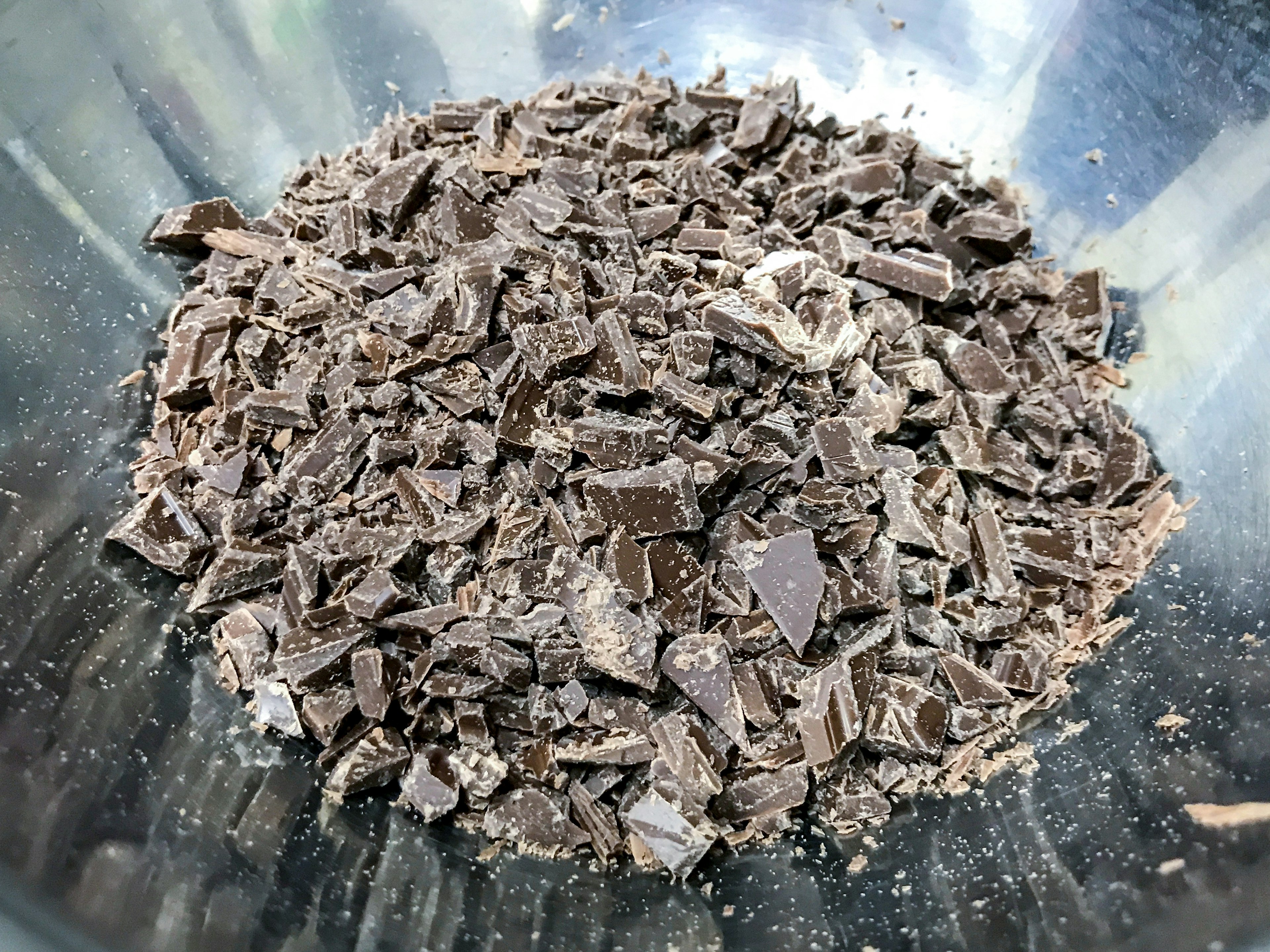 A mound of chopped dark chocolate in a glass bowl