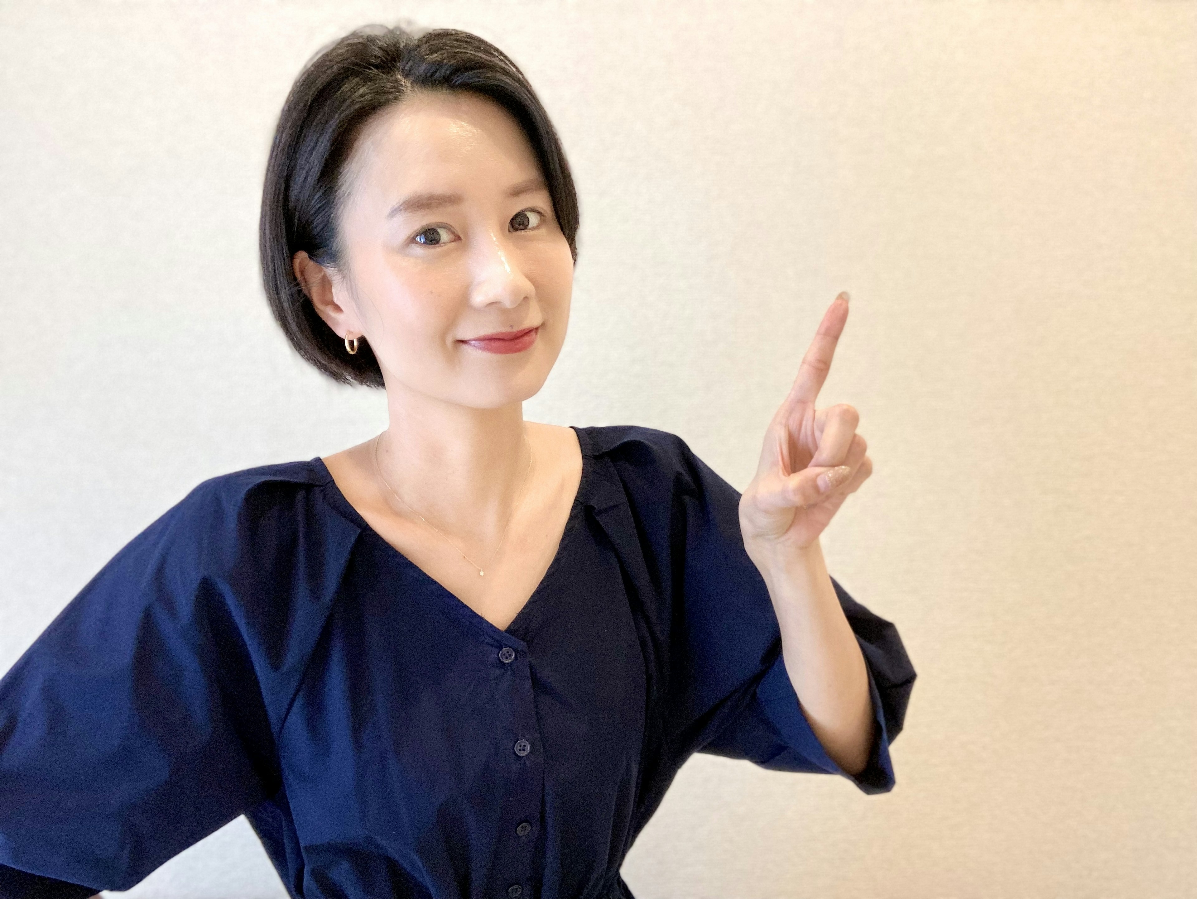 A woman in a blue outfit smiling and pointing with her finger