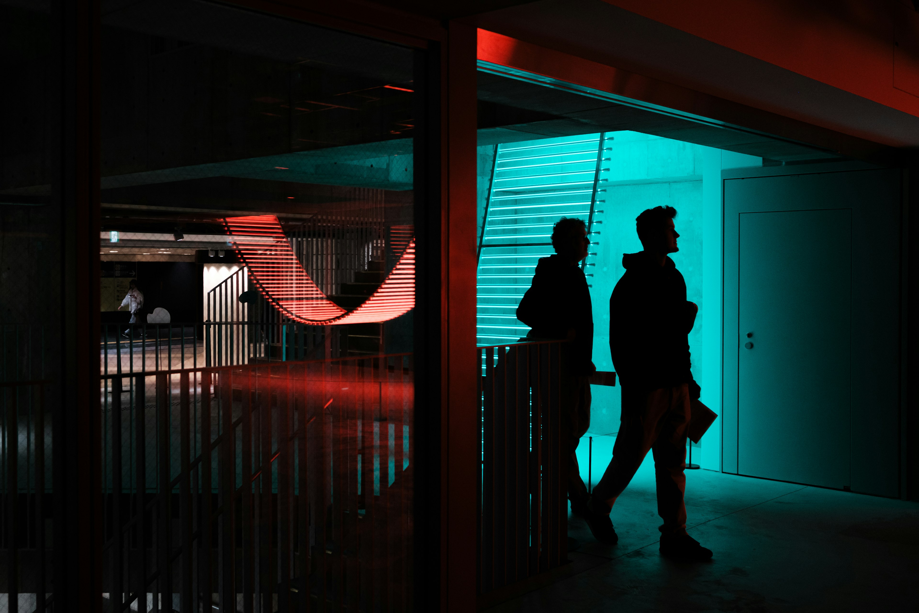 Silhouetten von zwei Personen, die in einem modernen Raum mit sich kreuzenden Licht- und Schatteneffekten gehen