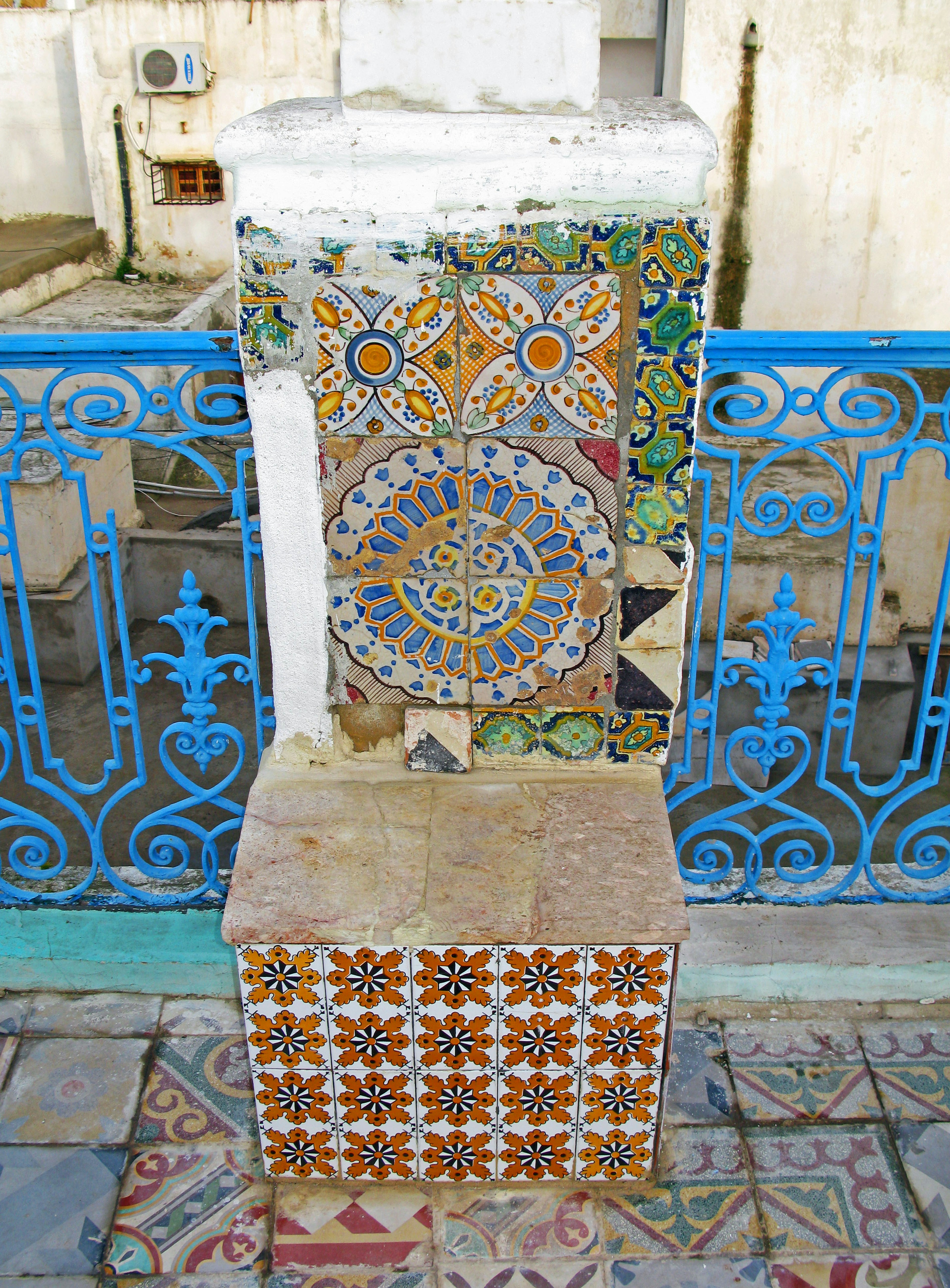 Colorful tiled bench with intricate patterns and blue wrought iron railing