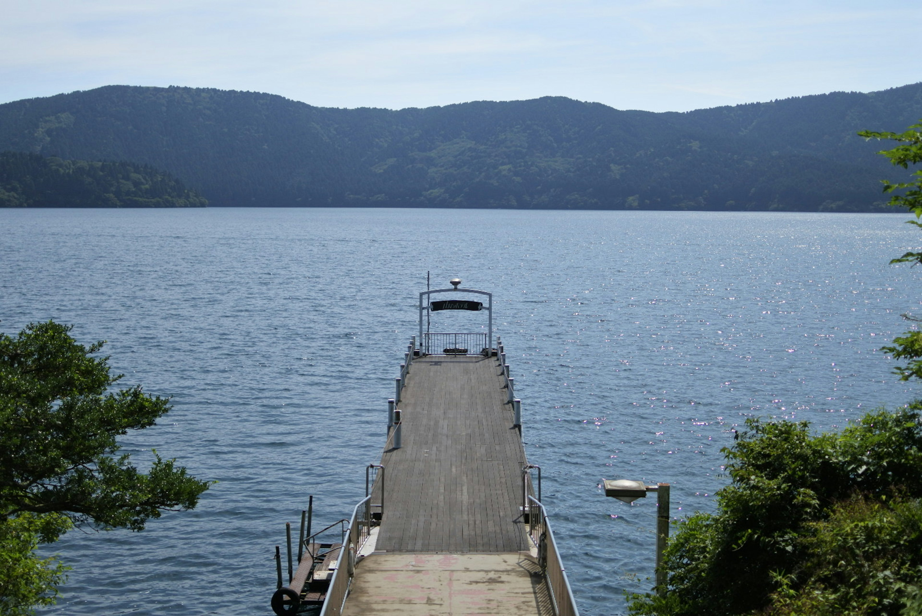 ท่าเรือที่ยื่นออกไปในทะเลสาบสงบและภูเขาในพื้นหลัง