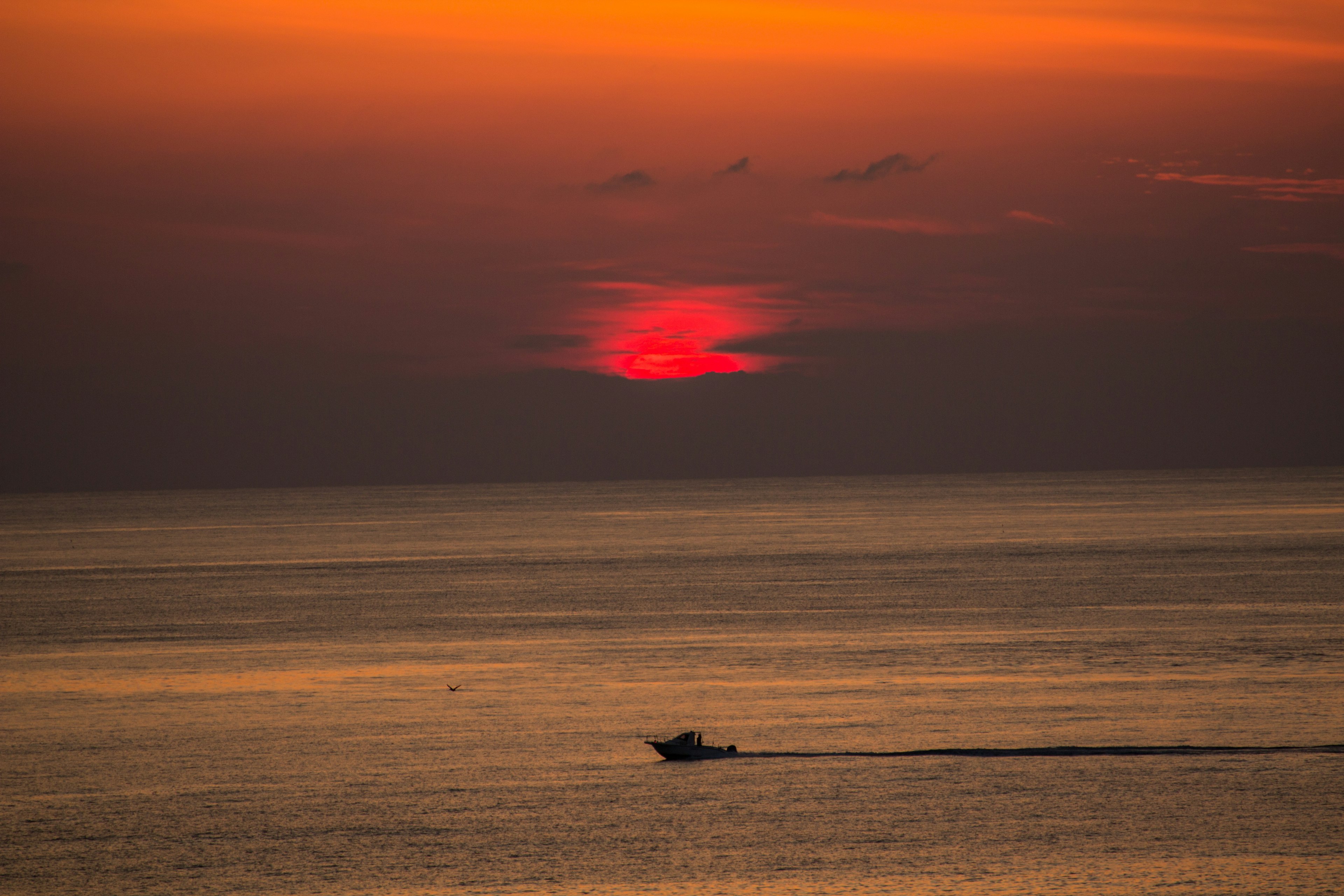 A small boat moving across the ocean during a vibrant sunset