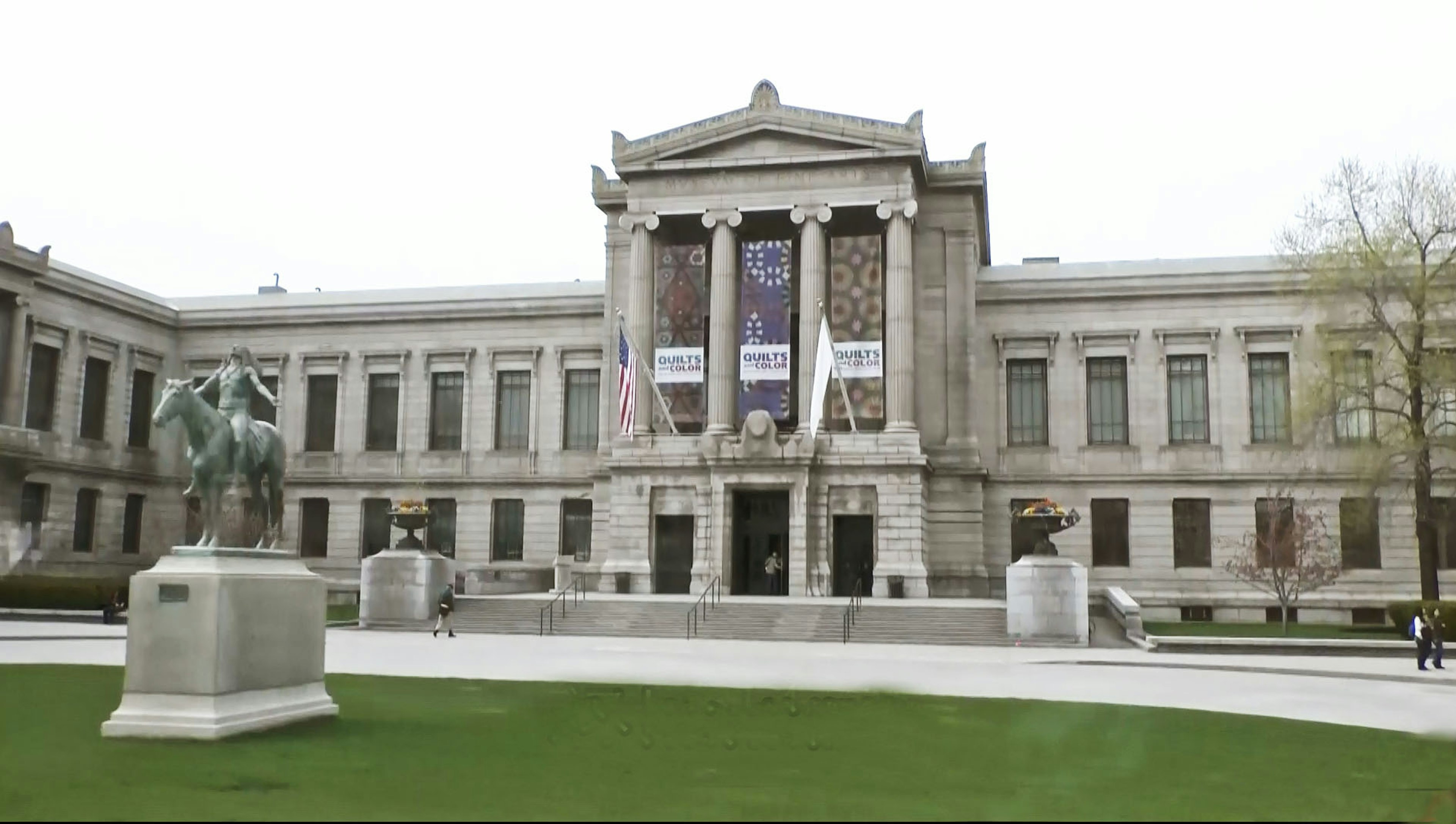 Außenansicht eines Kunstmuseums mit einer Statue auf einem grünen Platz