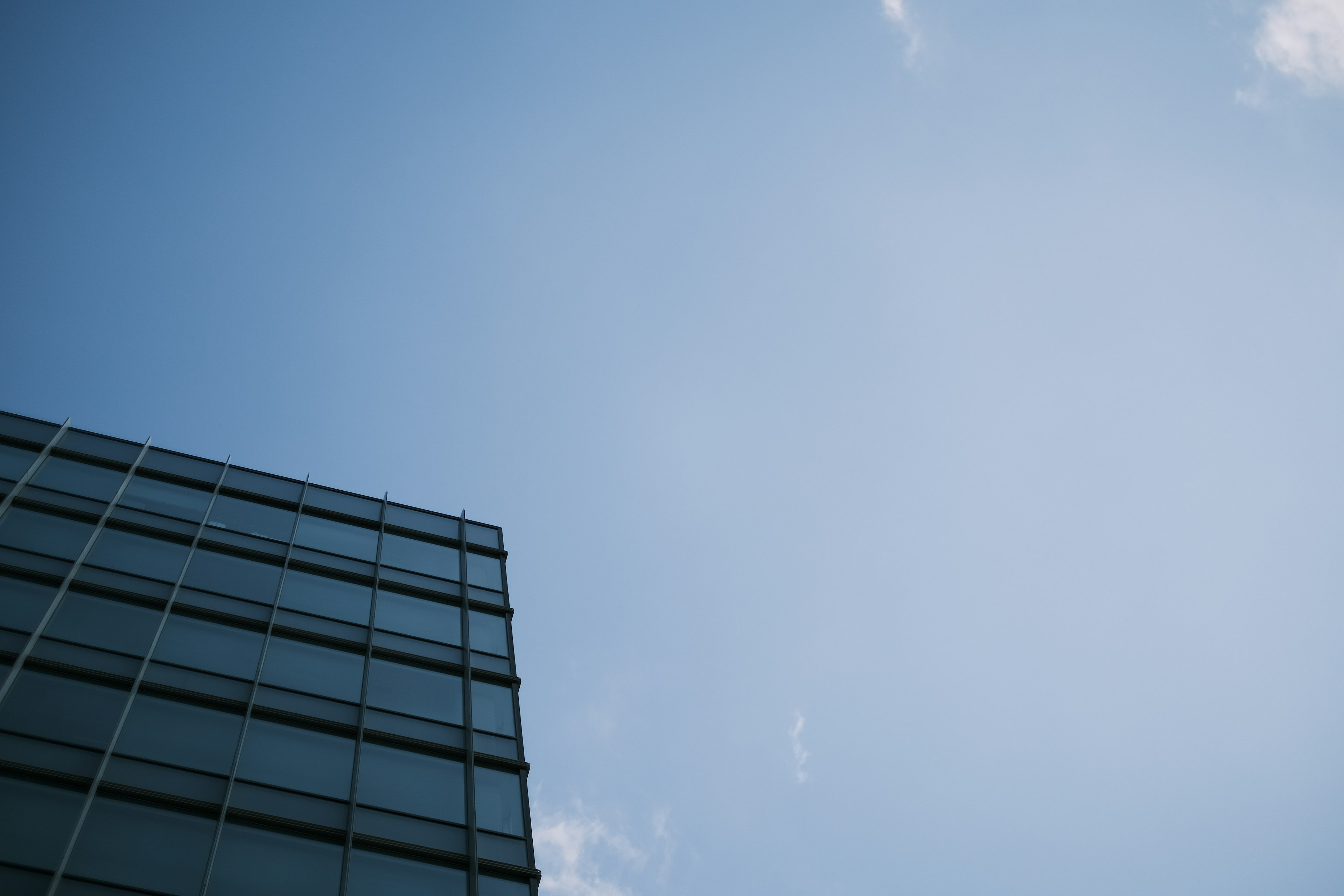 Part of a glass building against a blue sky