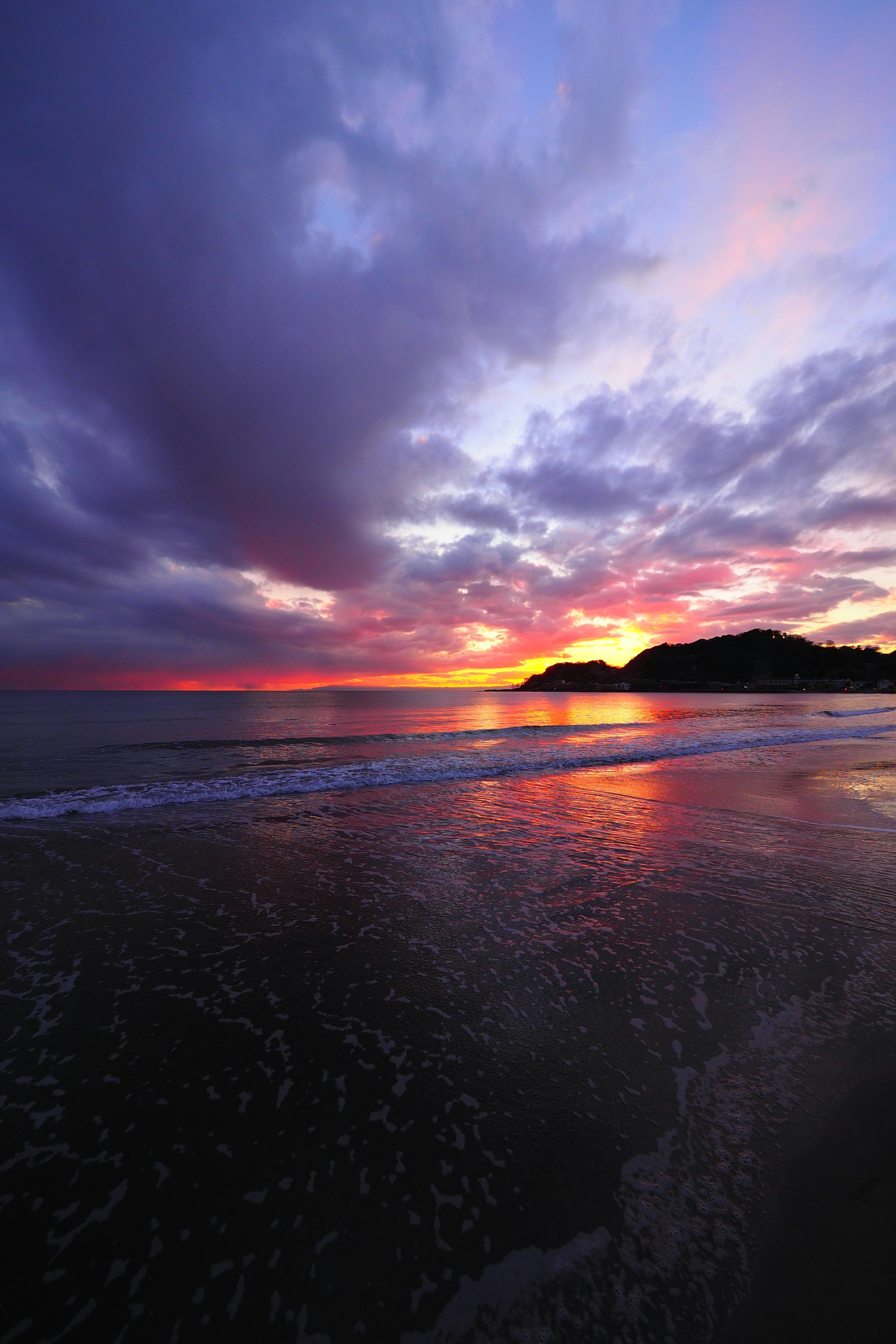 Tramonto vibrante che si riflette sulla superficie dell'oceano con nuvole colorate